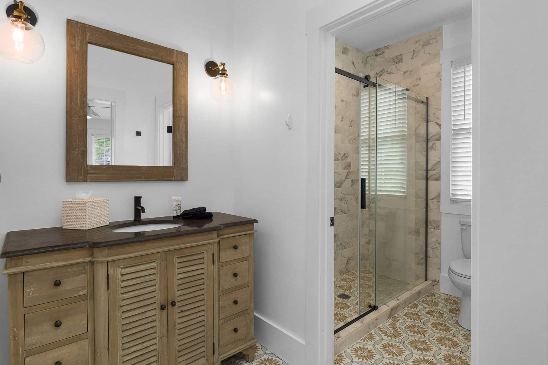 A bathroom with a sink , mirror , toilet and shower.