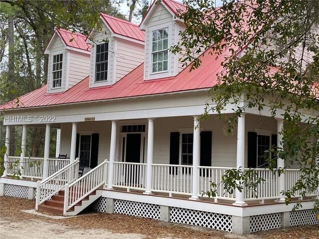 A white house with a red roof and a porch