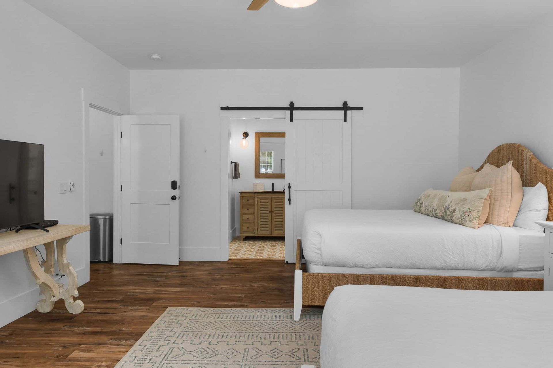 A bedroom with two beds , a television and a ceiling fan.