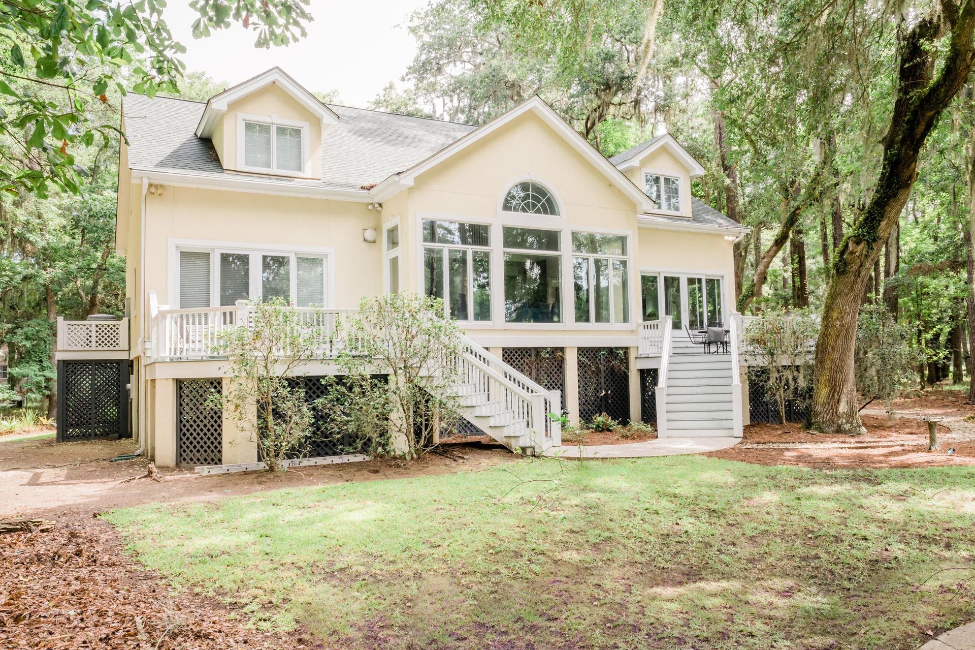 A large white house with a lot of windows is surrounded by trees.