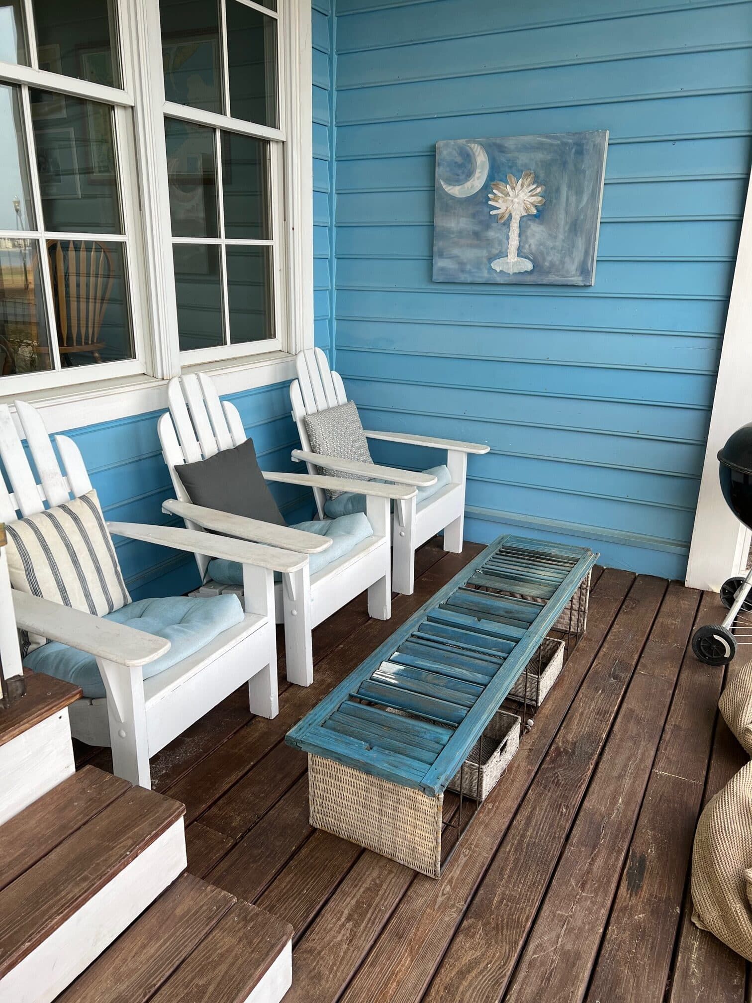 There are three chairs and a table on the porch.