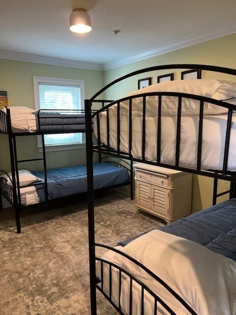 A bedroom with three bunk beds and a nightstand