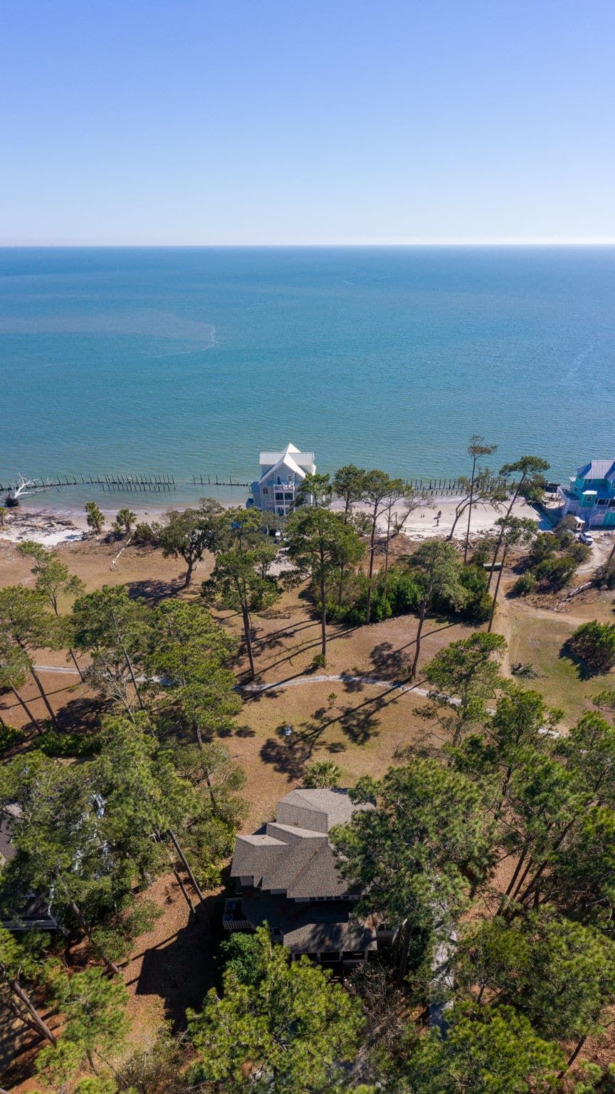 An aerial view of a house on a cliff overlooking the ocean.