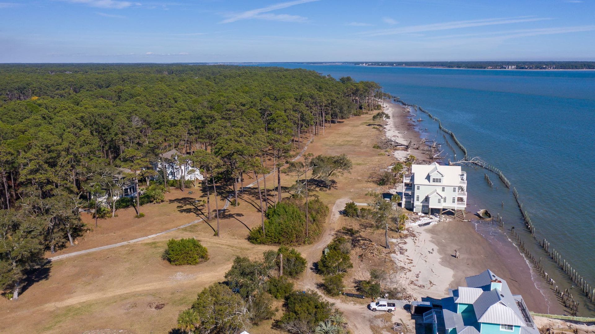 An aerial view of a house on the shore of a body of water surrounded by trees.