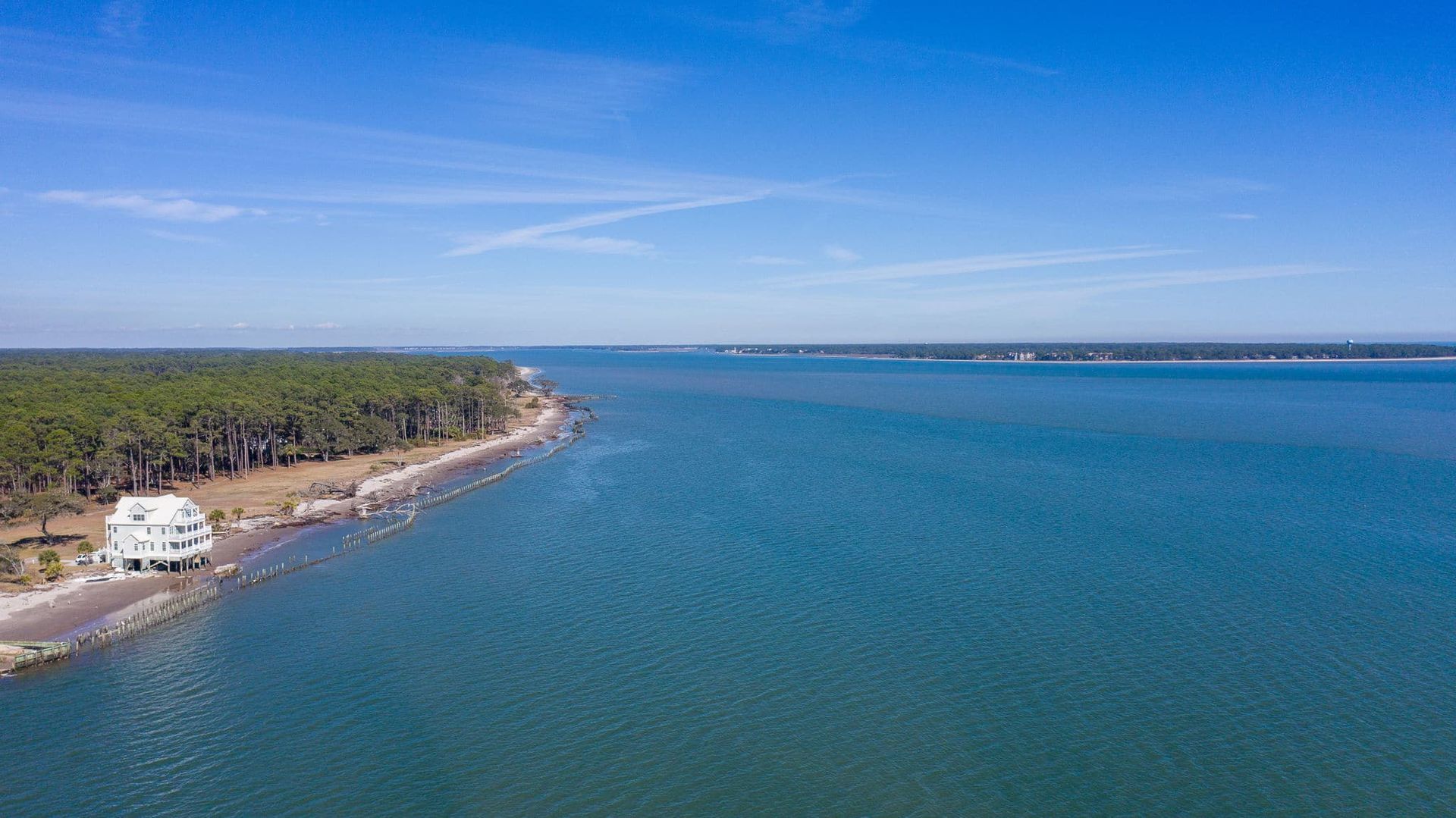An aerial view of a large body of water with a house on the shore.