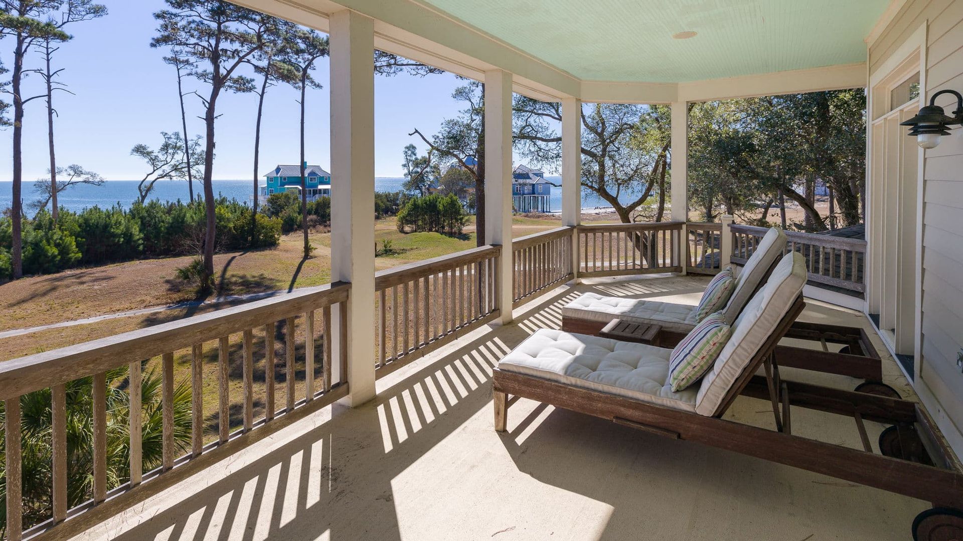 A porch with lounge chairs and a view of the ocean.