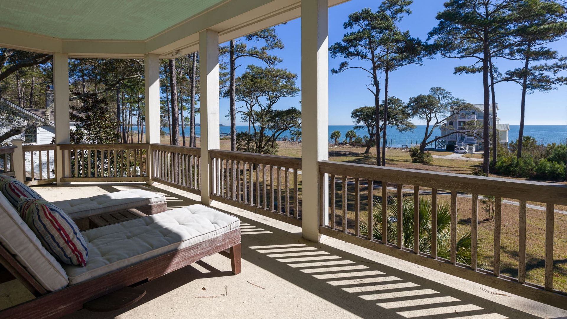 A porch with chairs and a railing overlooking the ocean.
