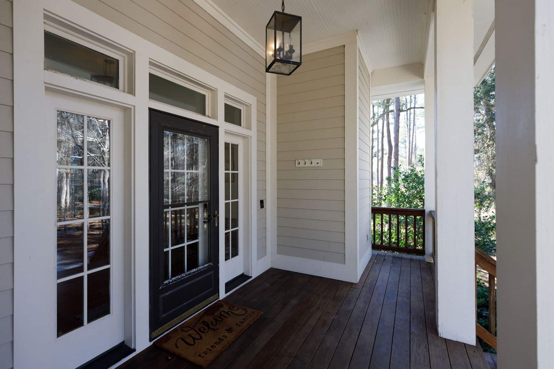 A porch with a welcome mat and a lantern hanging from the ceiling.