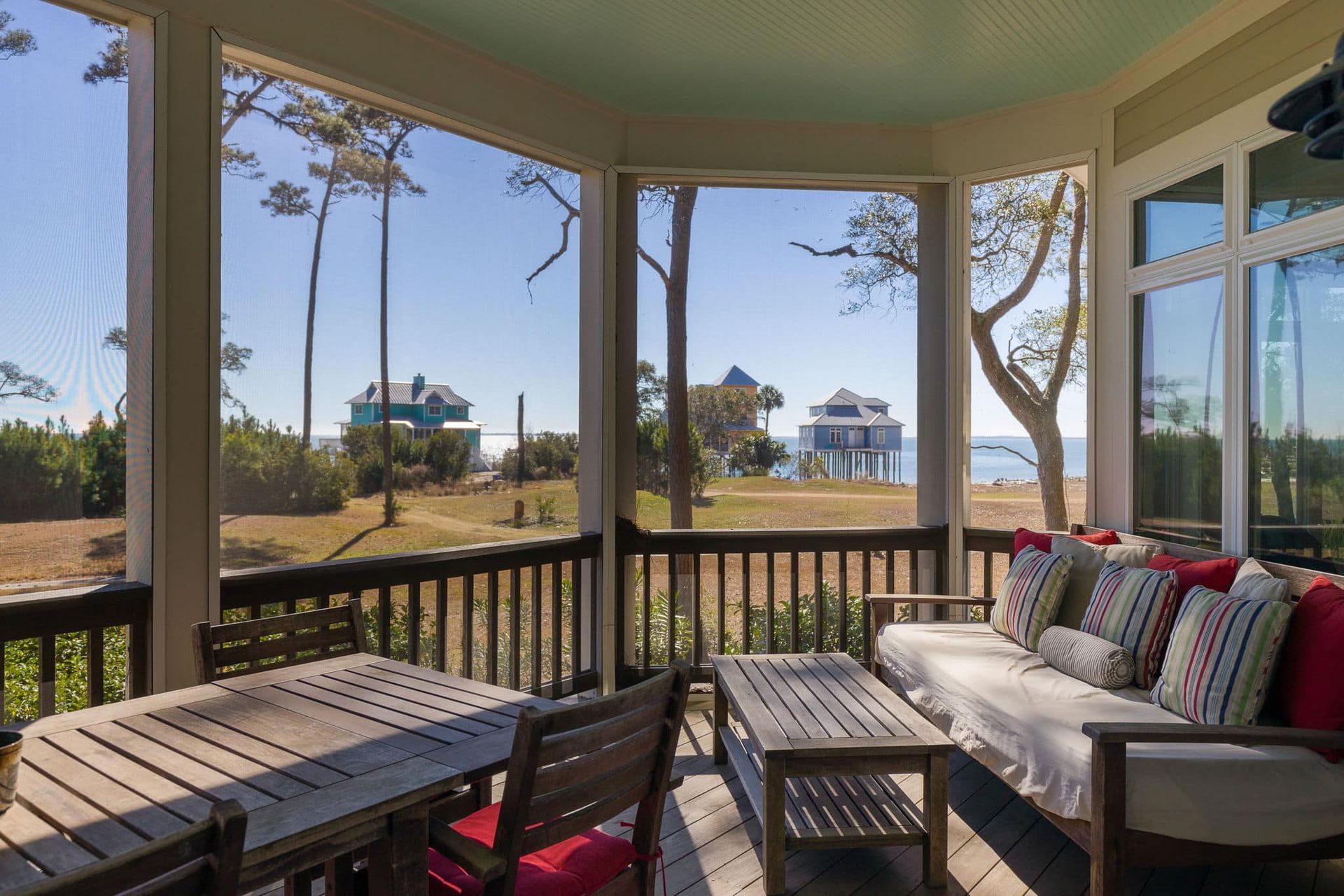 A screened in porch with a couch , table and chairs.