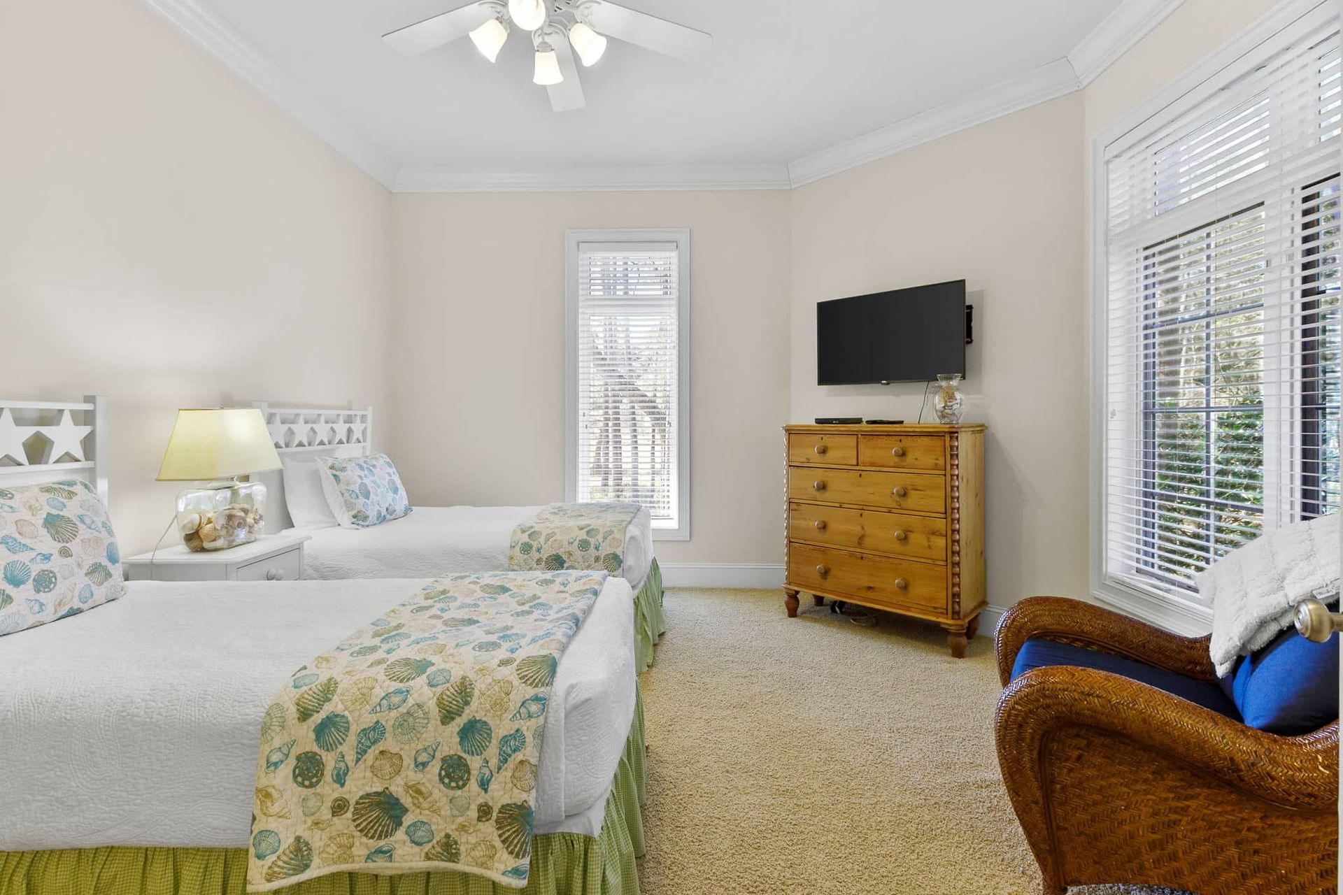 A bedroom with two beds , a dresser , and a television.