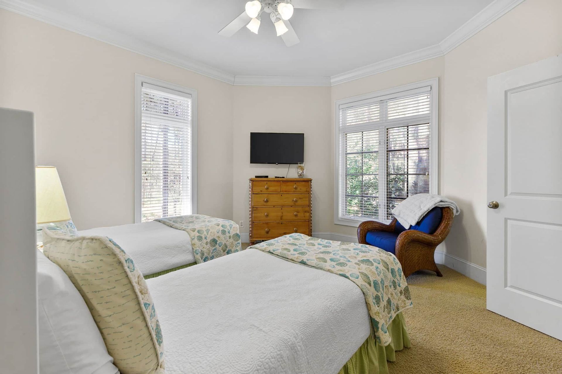 A bedroom with two beds , a chair , a dresser and a television.