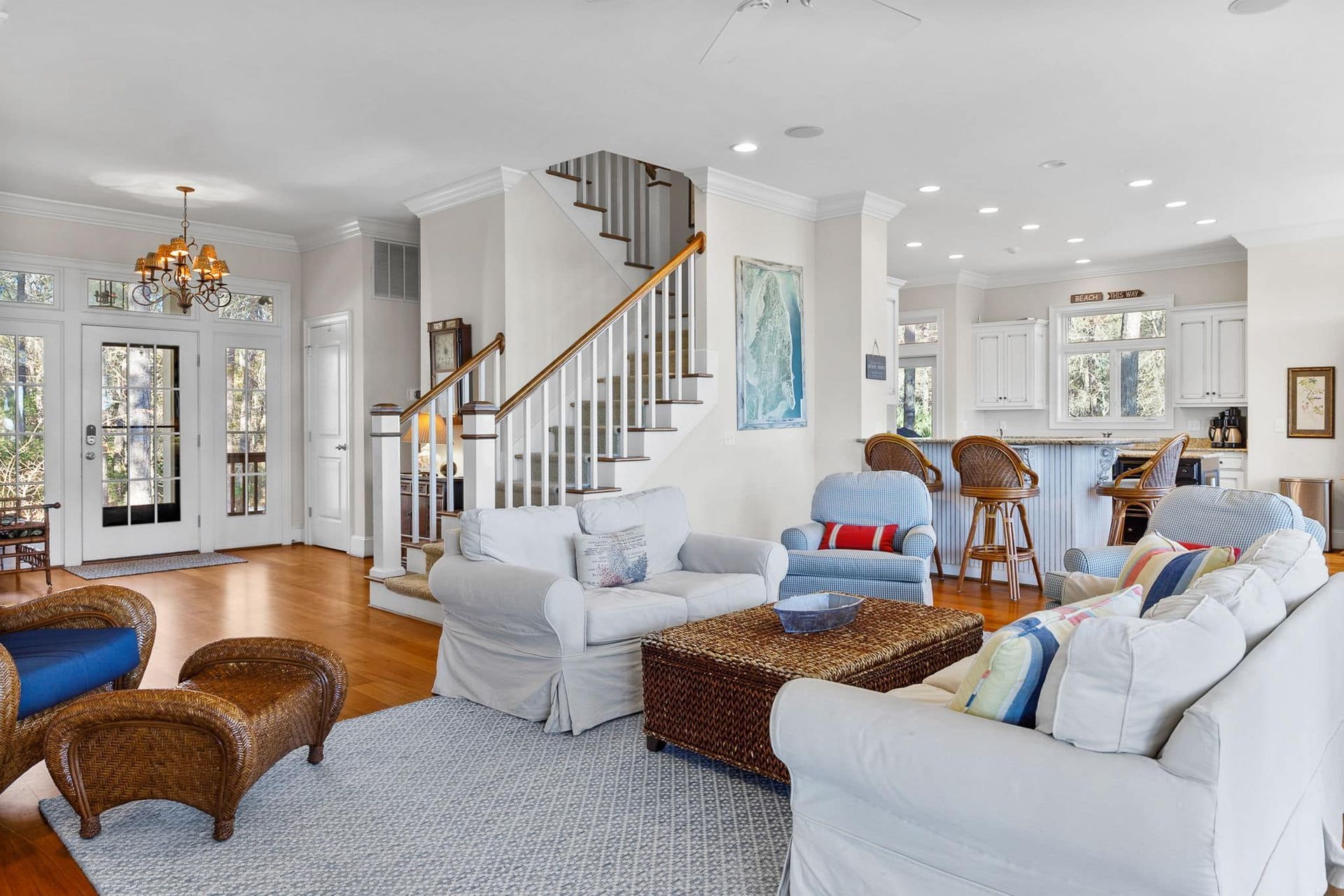 A living room with a couch , chairs , coffee table and stairs.