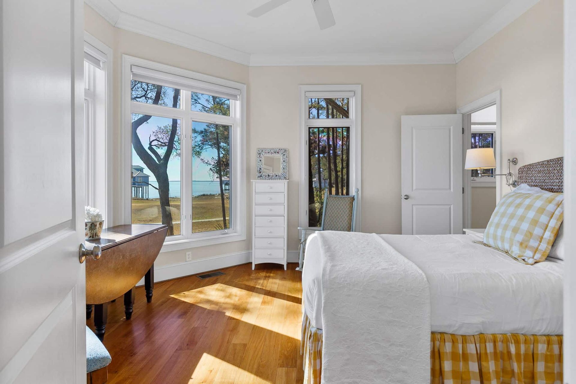 A bedroom with a bed , desk , chair , dresser and windows.