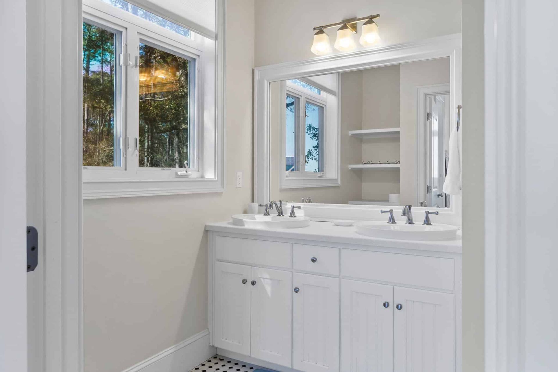 A bathroom with two sinks , a mirror and a window.