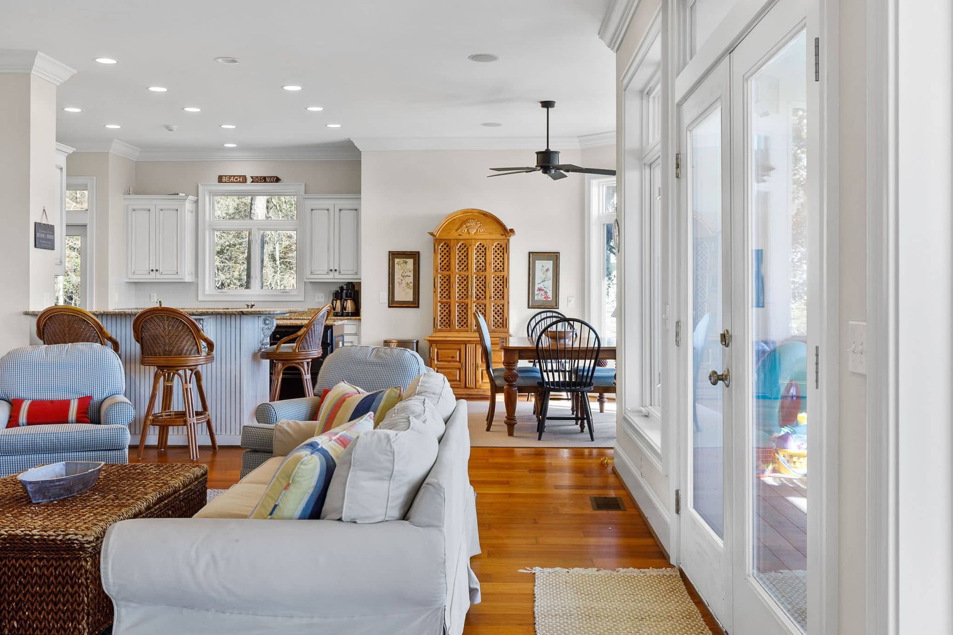 A living room with a couch , chairs , a table and a ceiling fan.