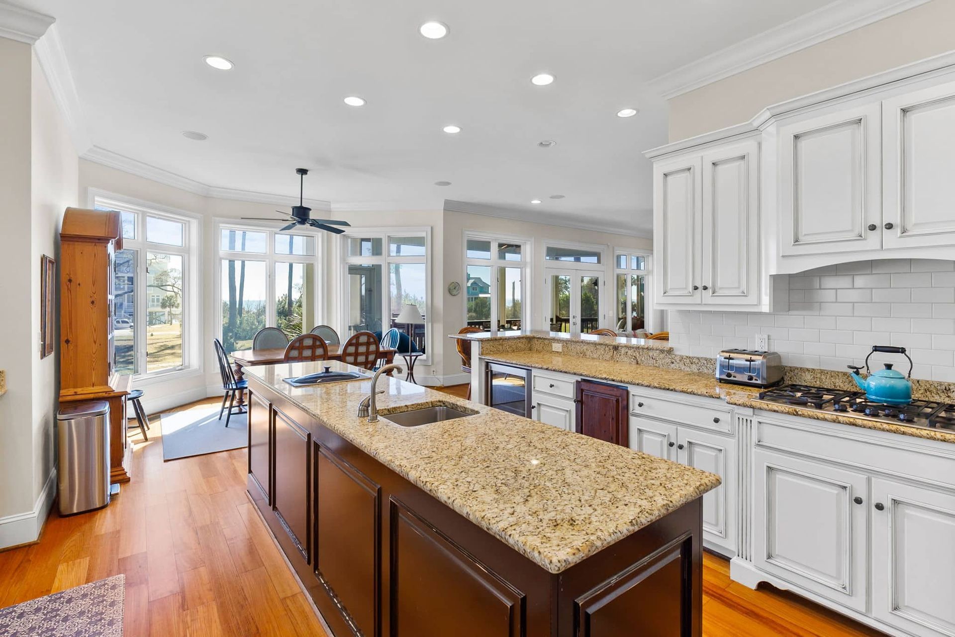 A kitchen with granite counter tops , white cabinets , and a large island.