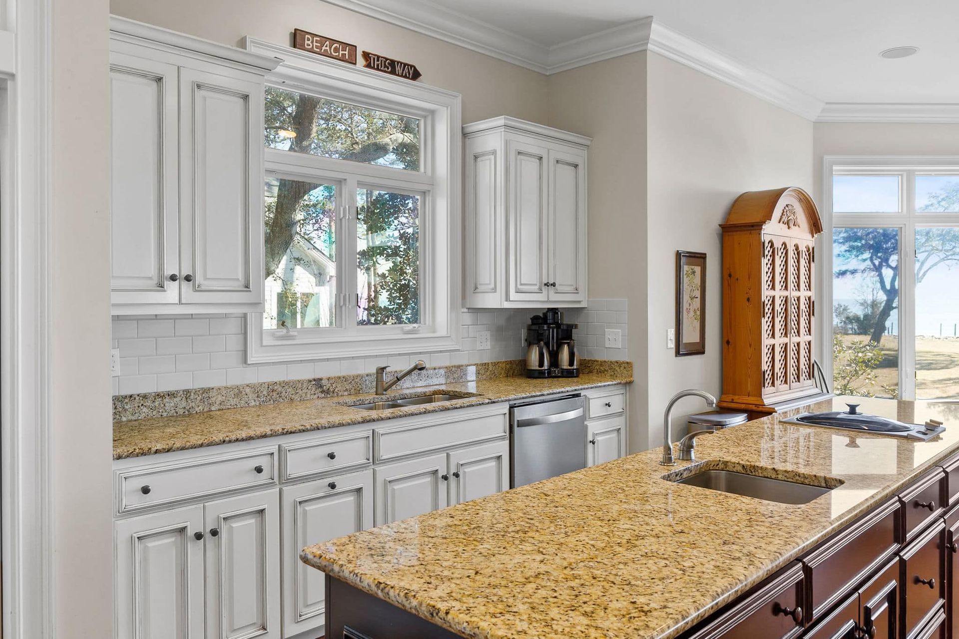 A kitchen with white cabinets , granite counter tops , a sink , and a large island.
