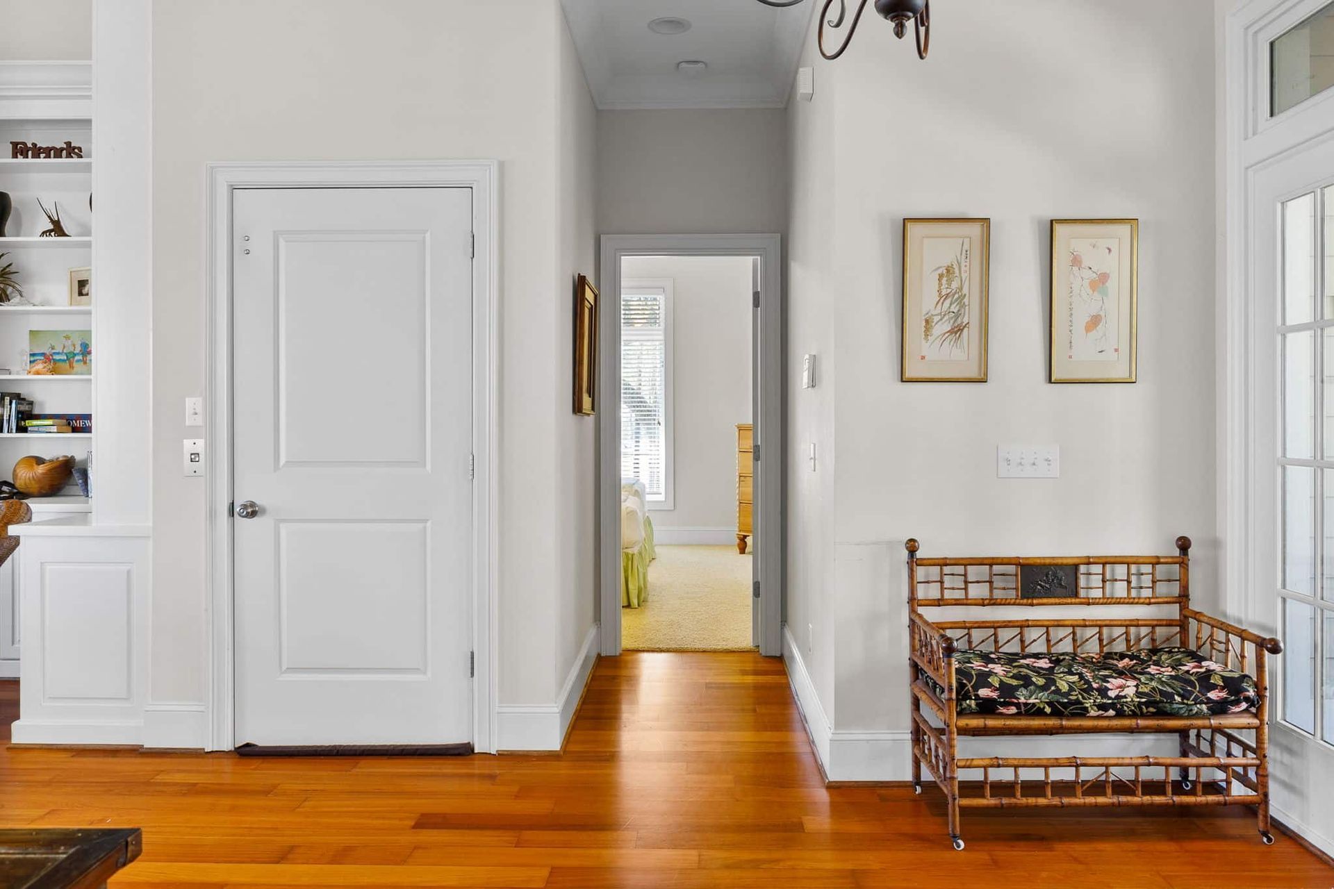 A hallway in a house with hardwood floors and a bench.