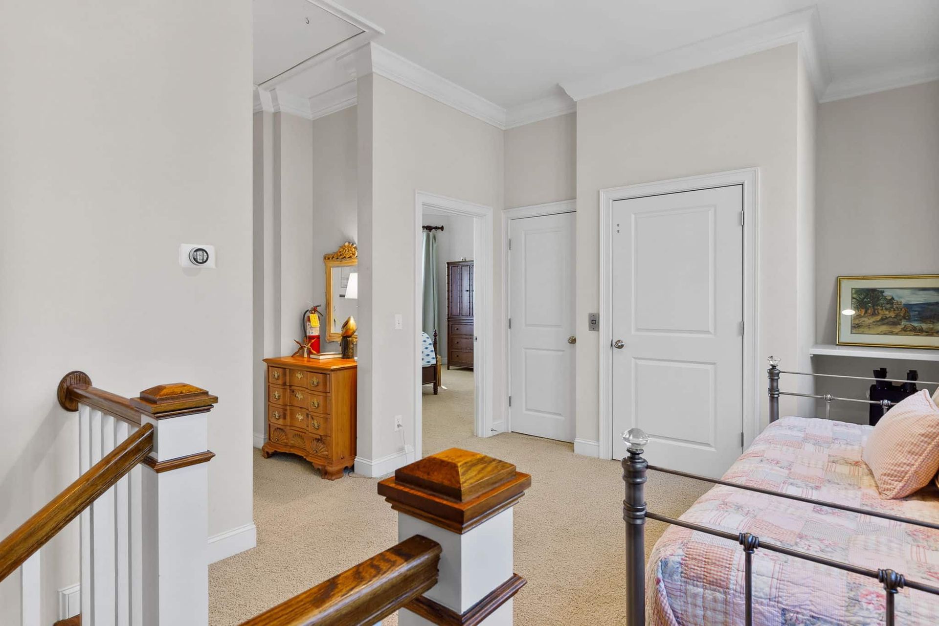 A bedroom with a bed , dresser , mirror and stairs.