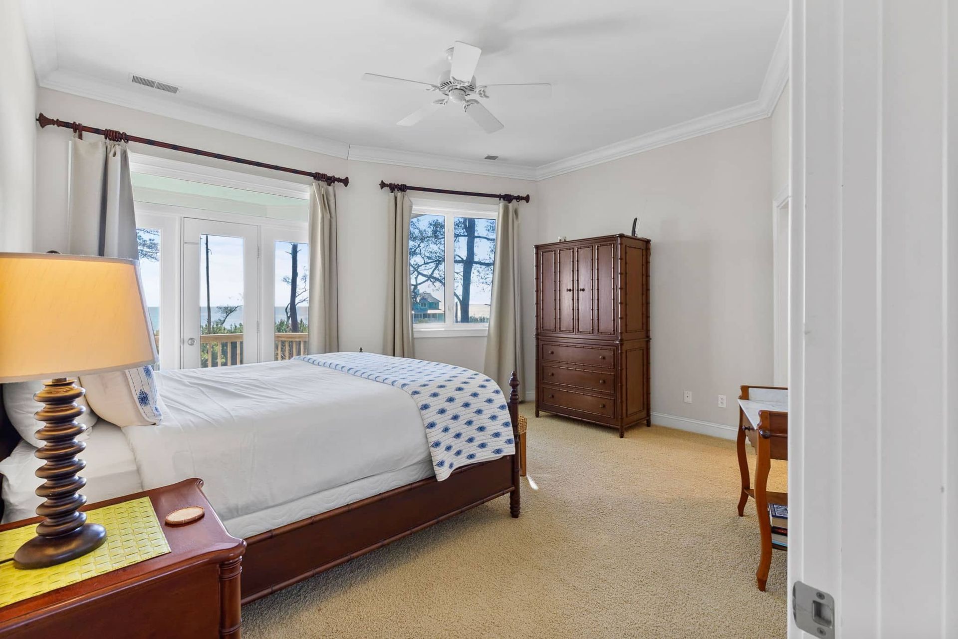 A bedroom with a king size bed , nightstand , lamp and a ceiling fan.