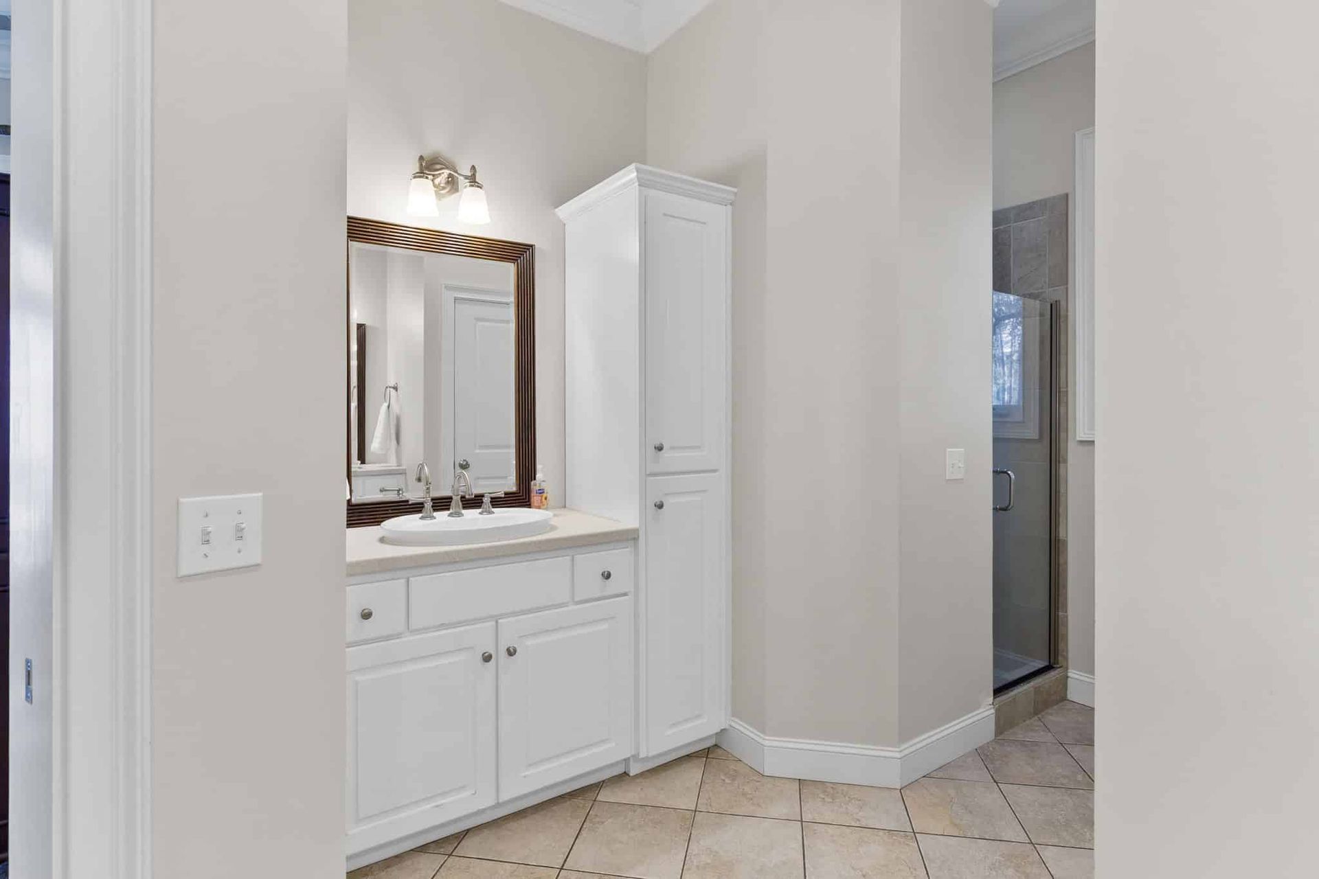 A bathroom with a sink , mirror and cabinets.