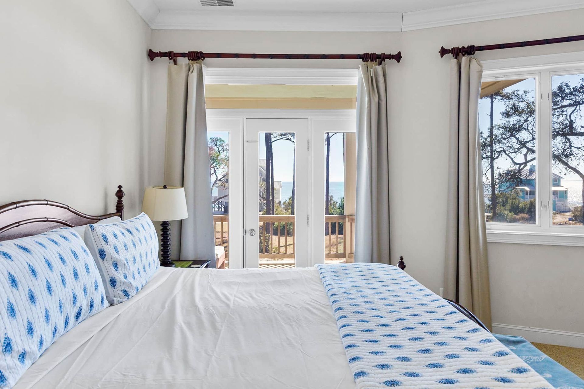 A bedroom with a king size bed , a lamp , a window and a balcony.