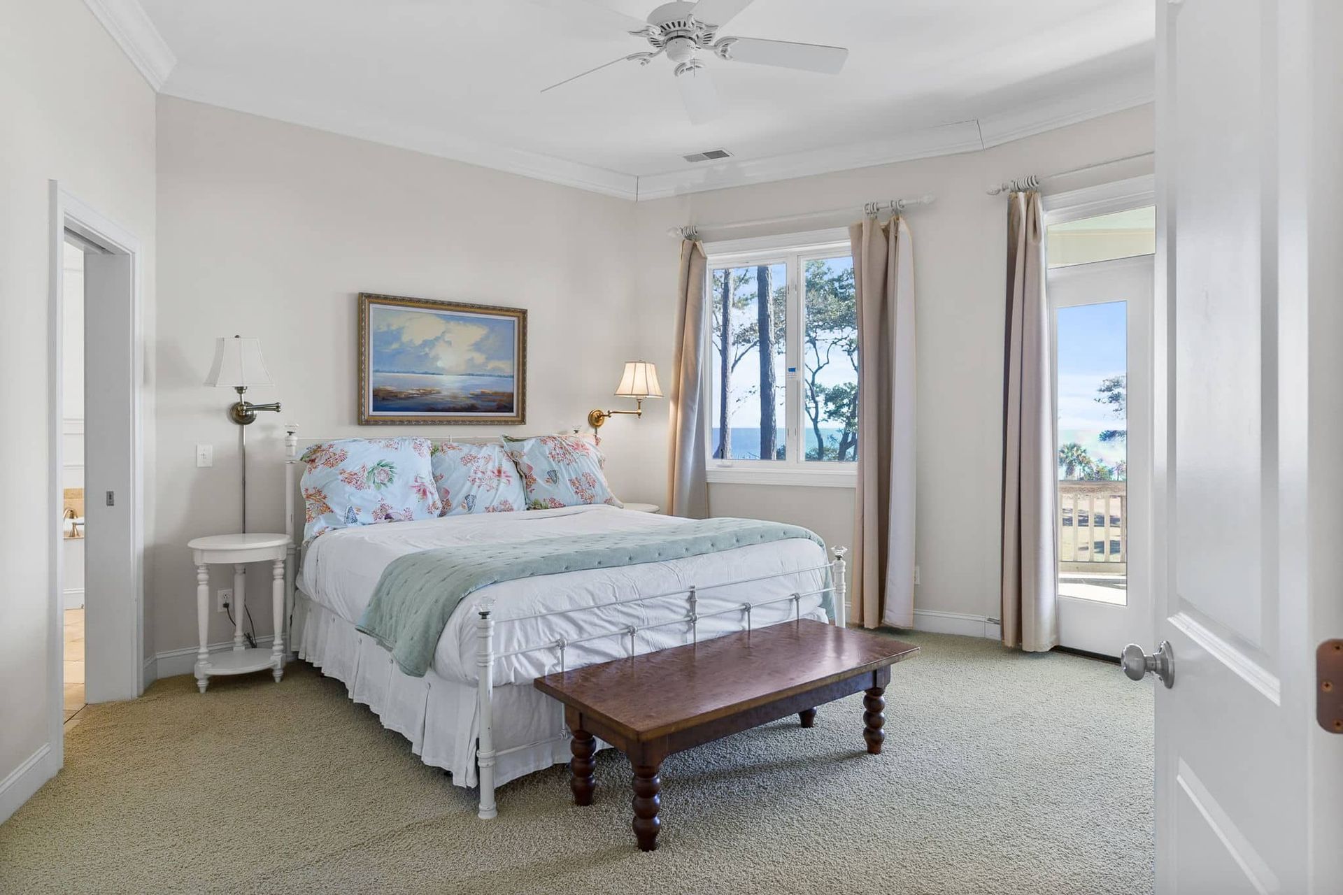 A bedroom with a king size bed , a bench , and a ceiling fan.