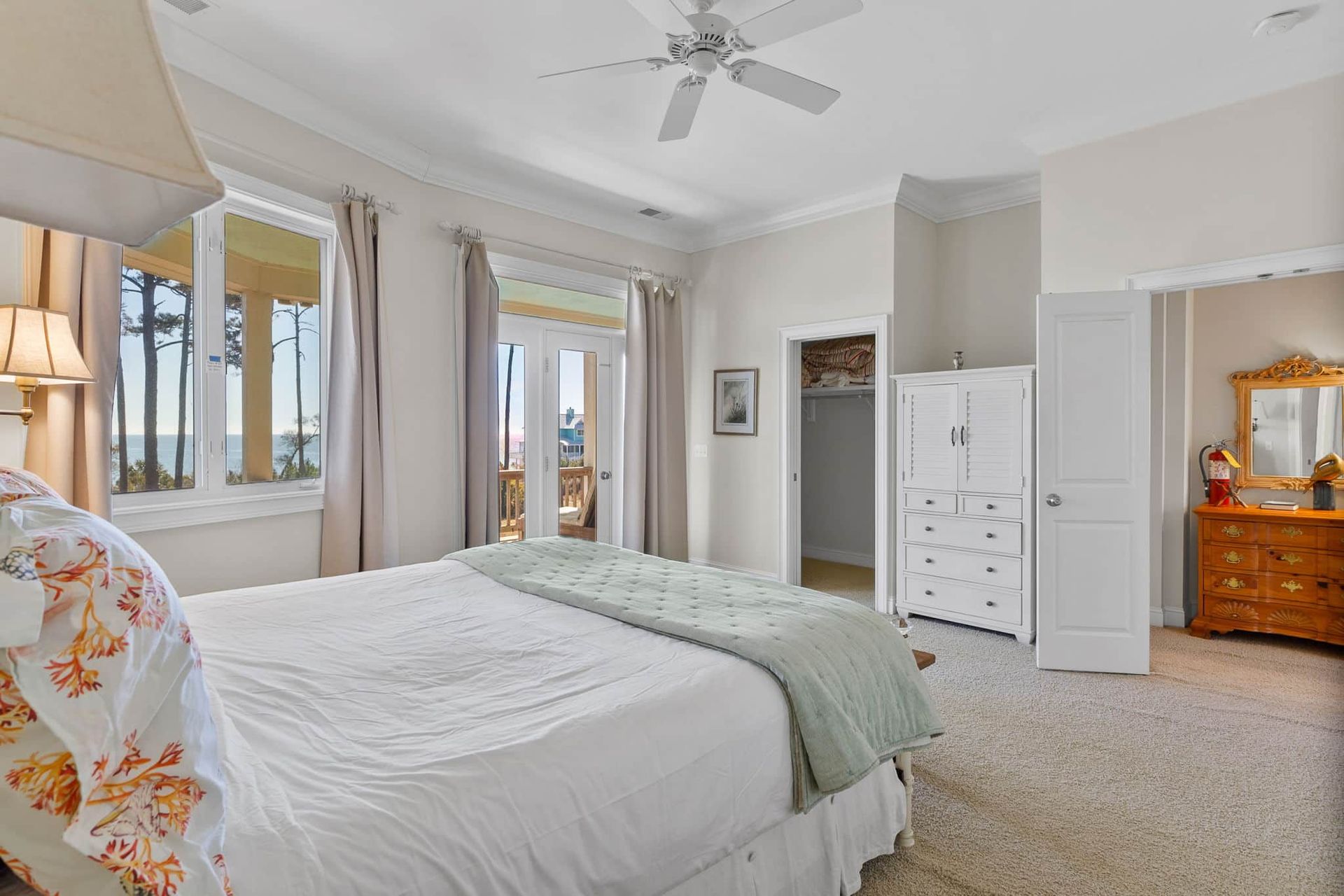 A bedroom with a king size bed , dresser , mirror and ceiling fan.