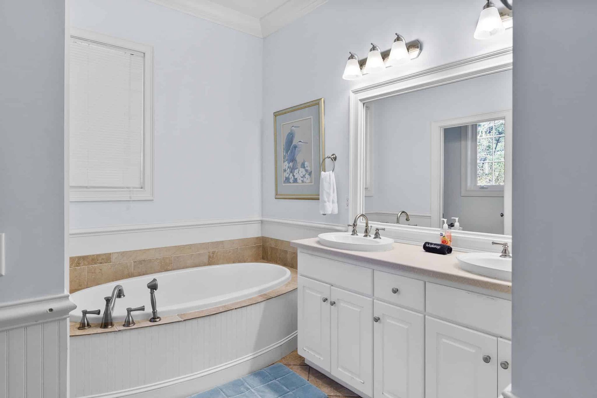 A bathroom with two sinks , a tub , and a mirror.