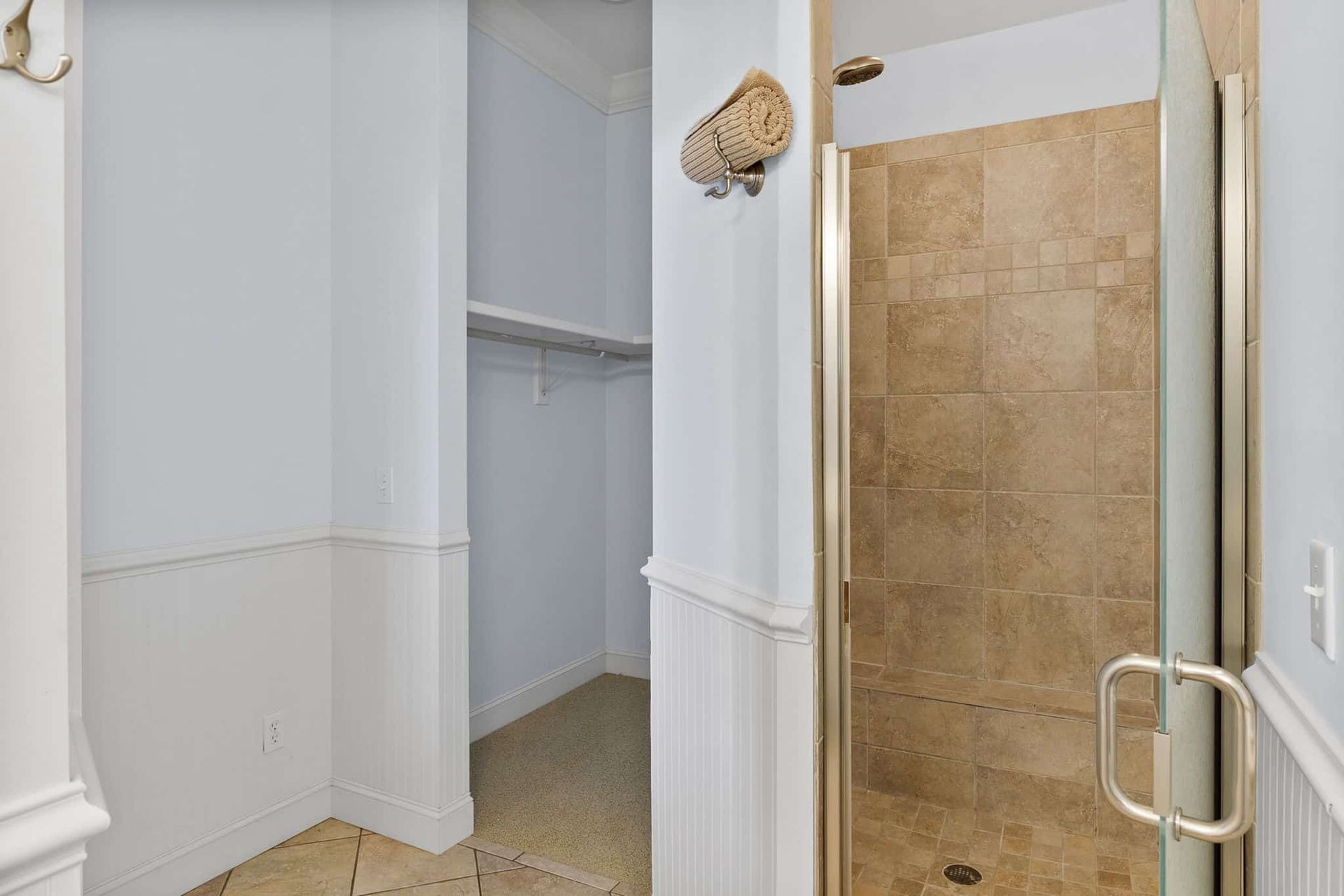 A bathroom with a walk in shower and a closet.
