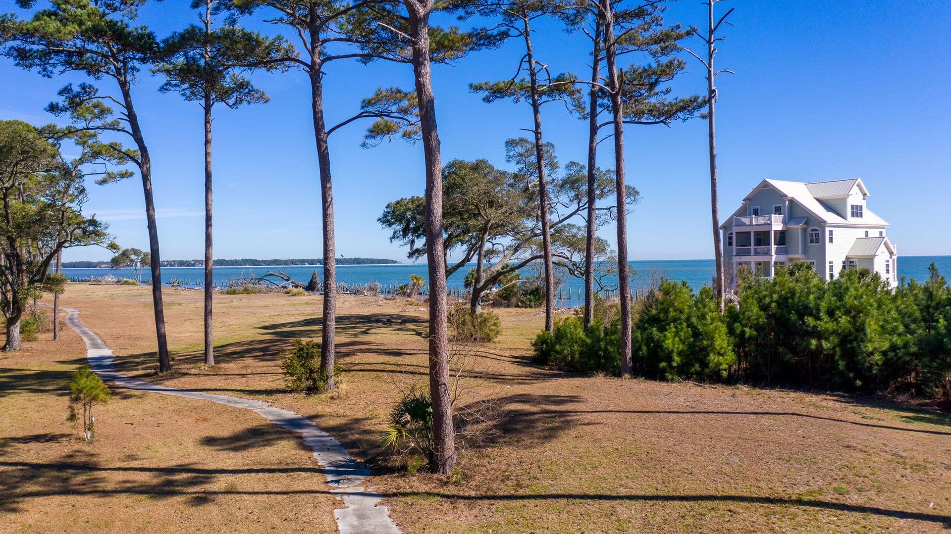 A house is sitting on top of a hill next to a body of water surrounded by trees.