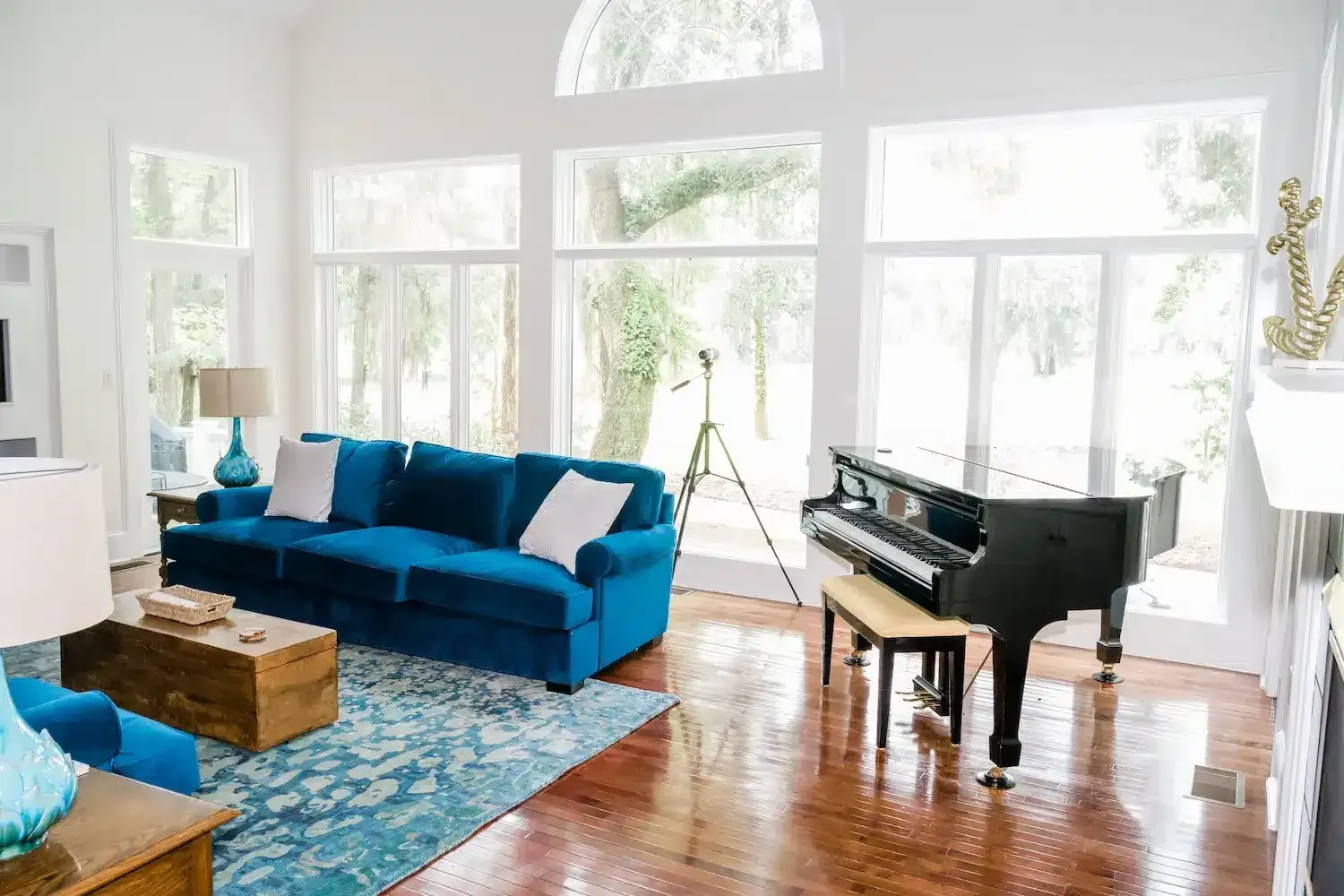 A living room with a blue couch and a black piano.