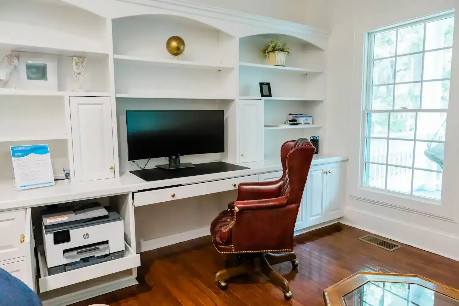 A living room with a desk , chair , computer and printer.