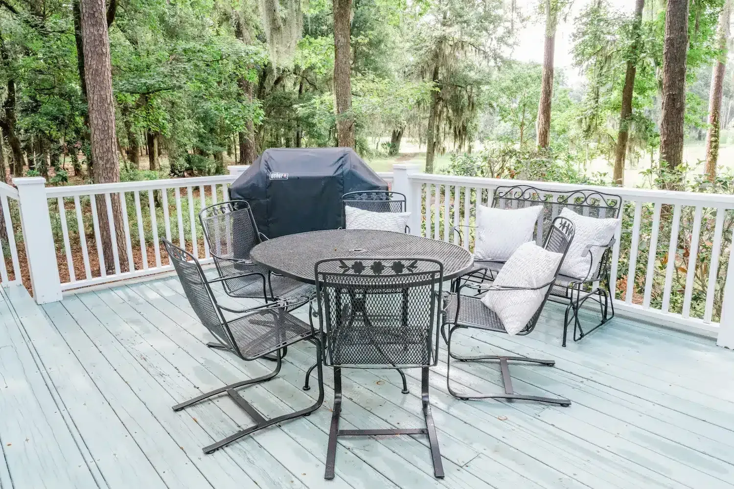 A deck with a table and chairs and a grill.