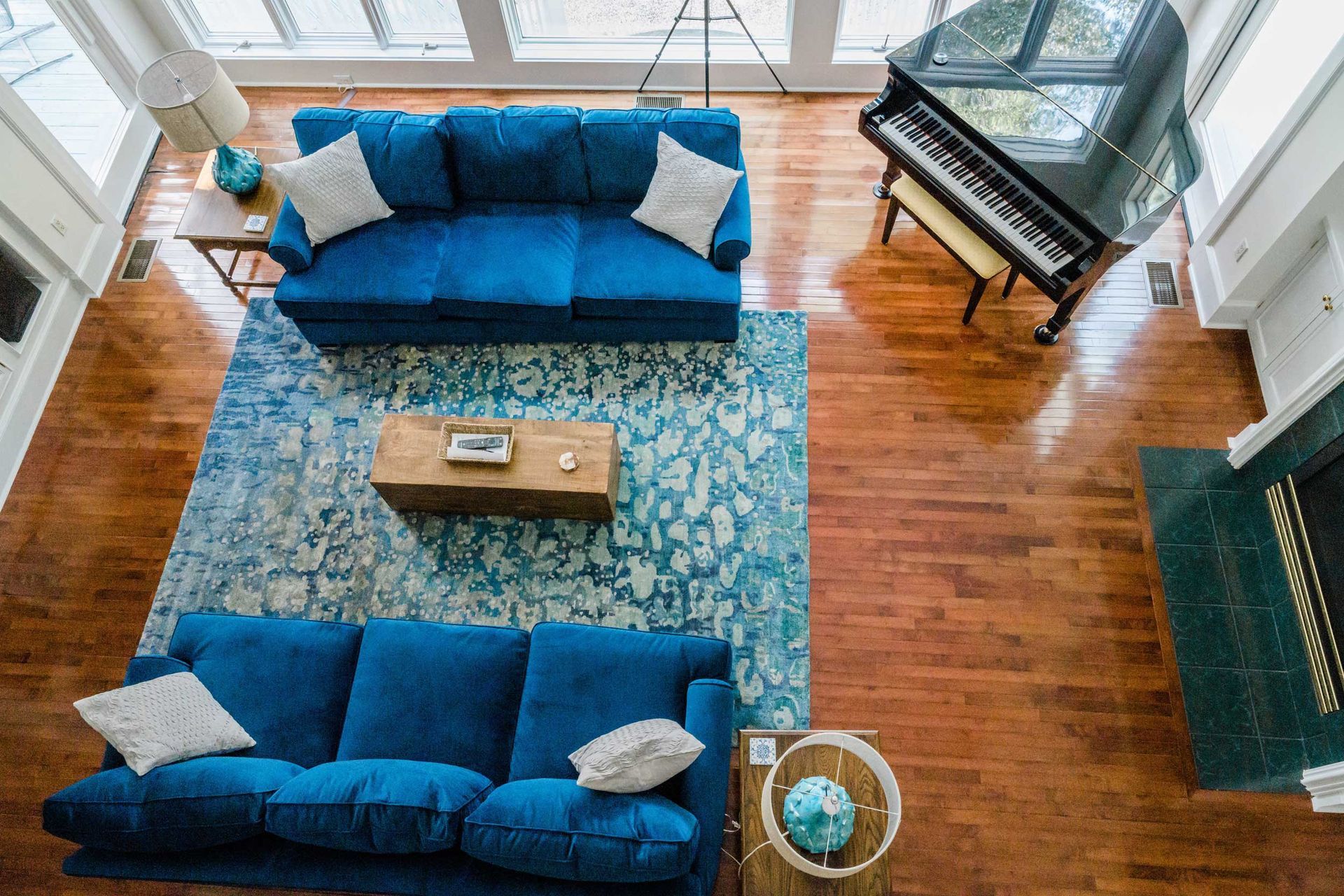 An aerial view of a living room with a blue couch and a piano.