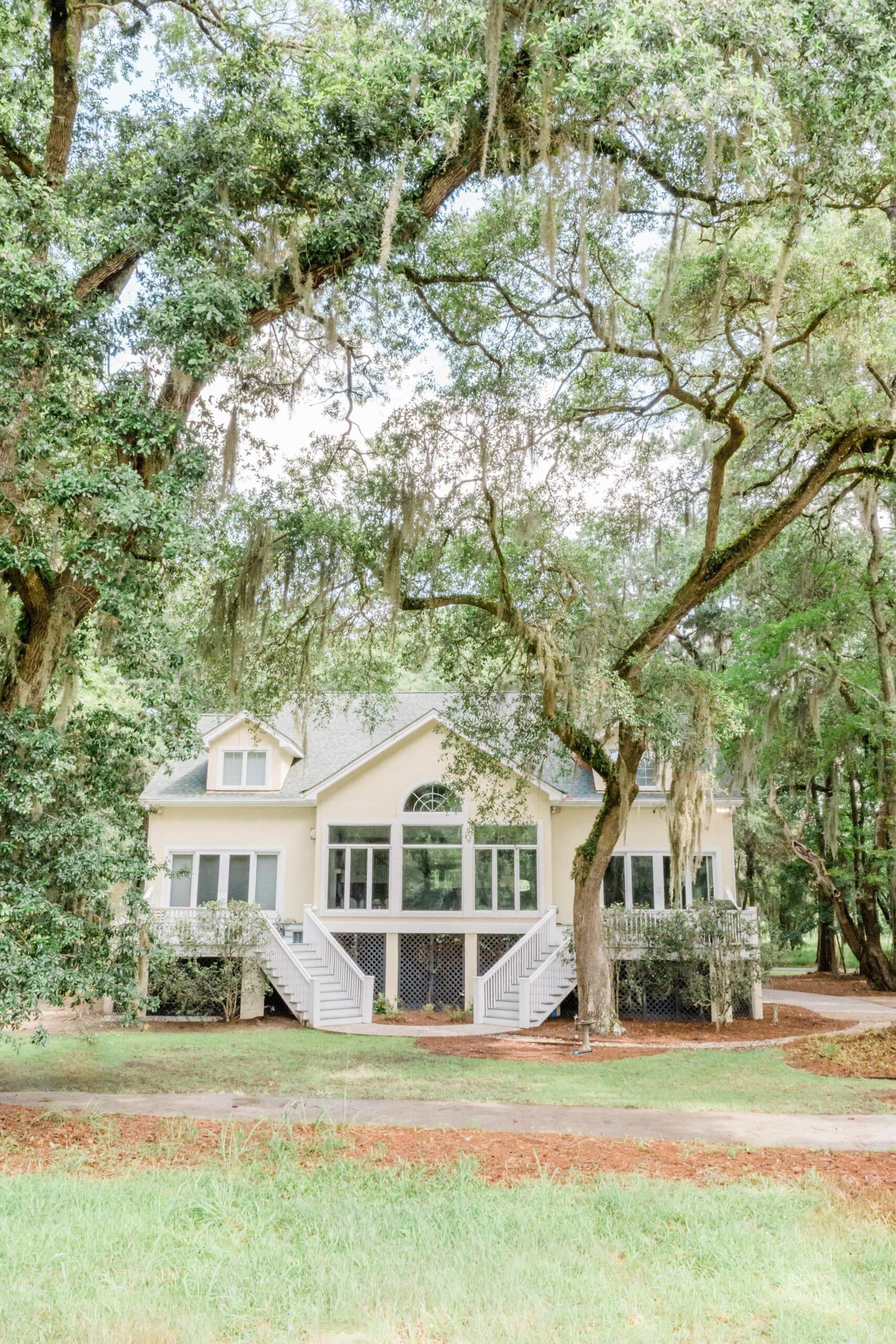 A large white house is surrounded by trees and grass.