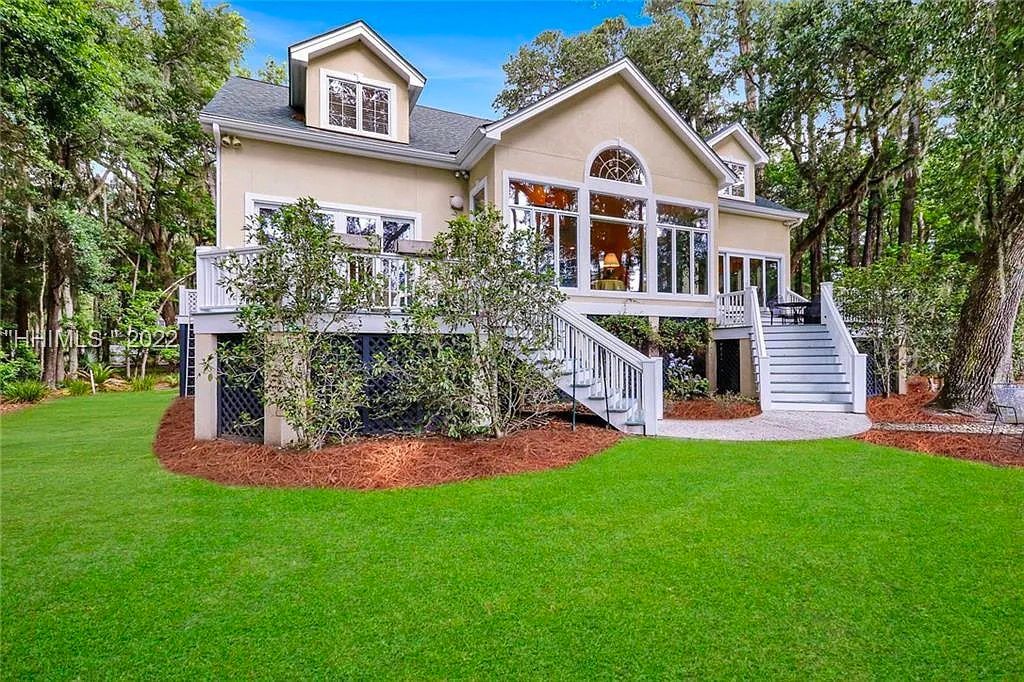 A large house with a large lawn in front of it surrounded by trees.