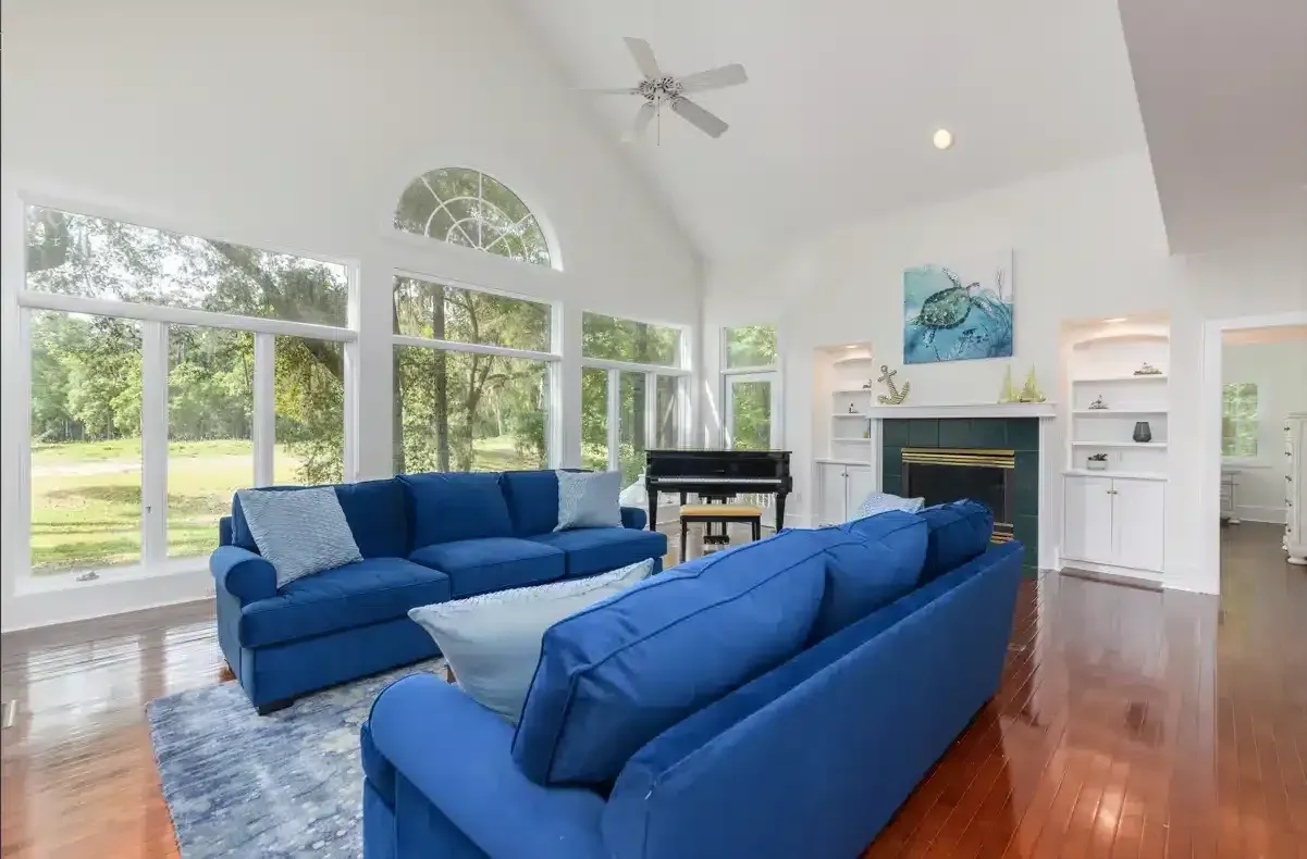 A living room with blue couches , a fireplace , and a piano.