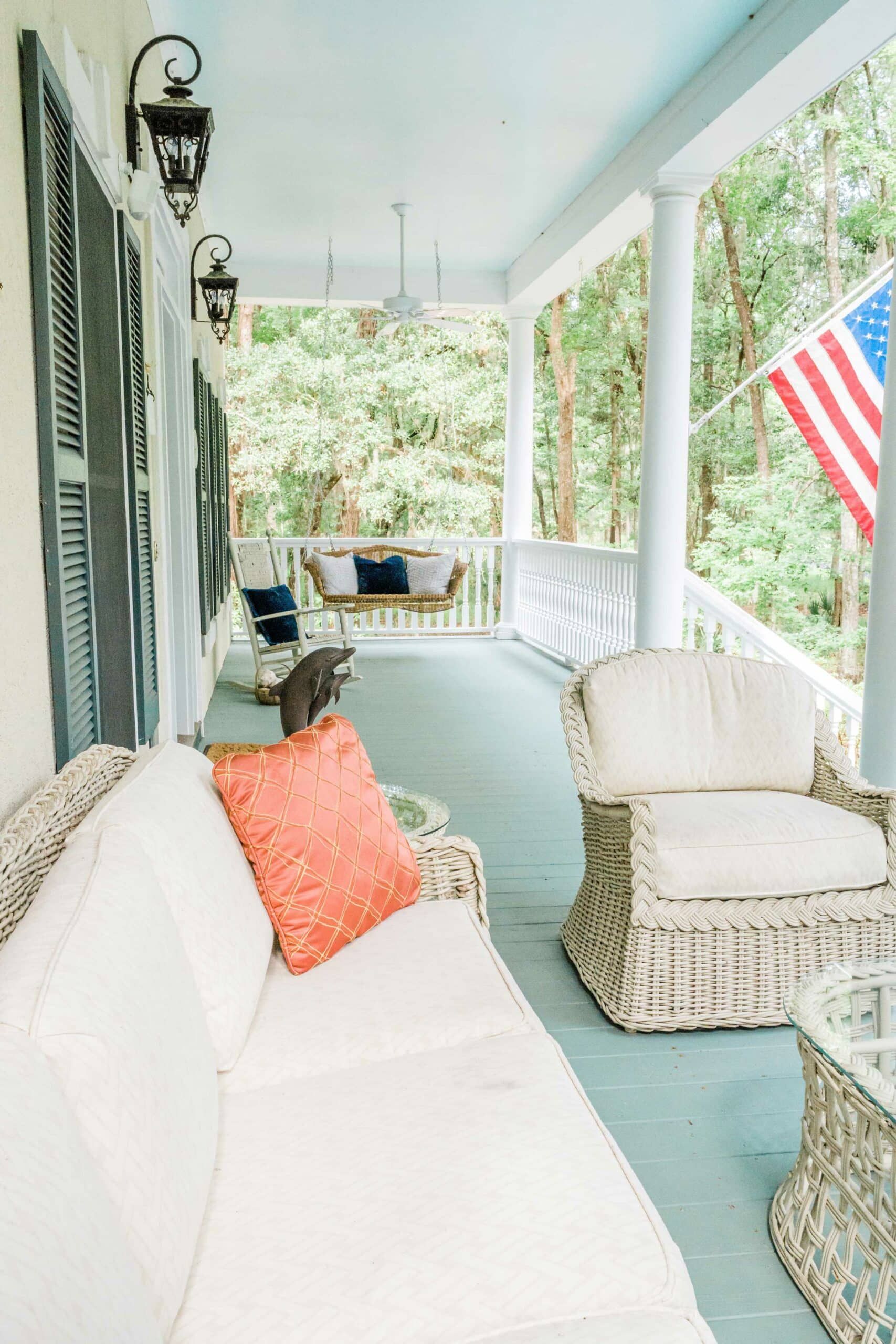 A porch with a couch and chairs and an american flag.