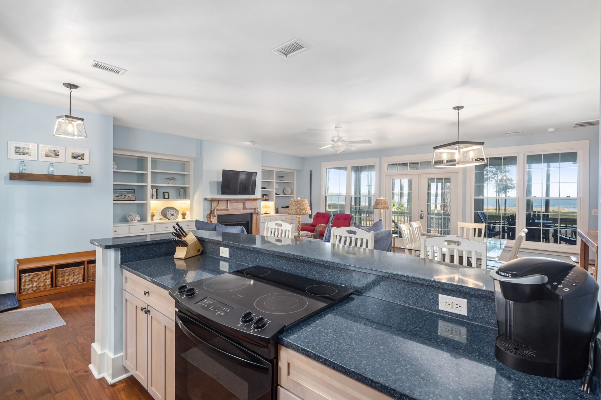 A kitchen with a stove , sink , and a view of the ocean.