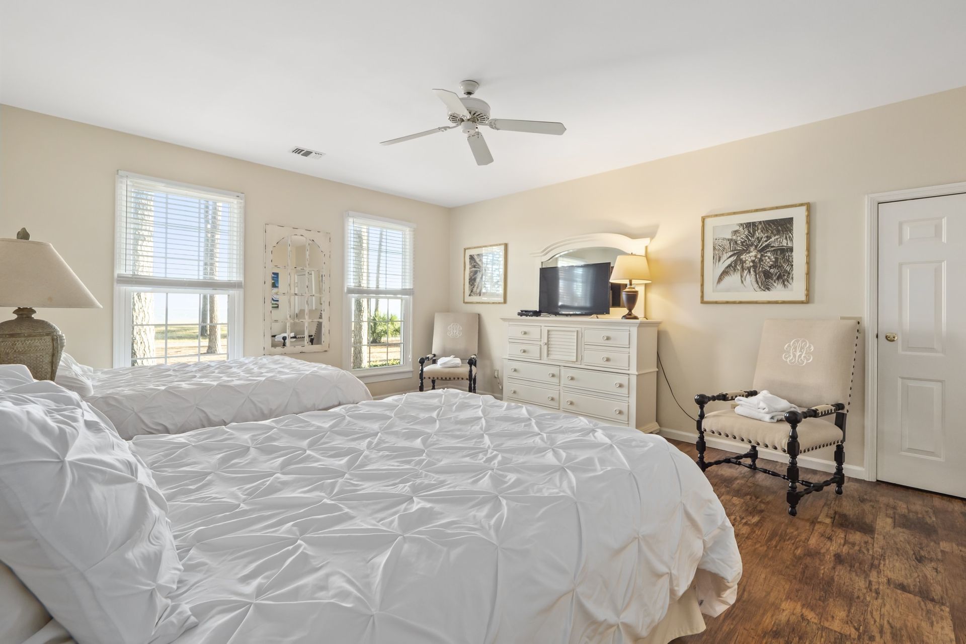 A bedroom with two beds , a dresser , a chair and a television.