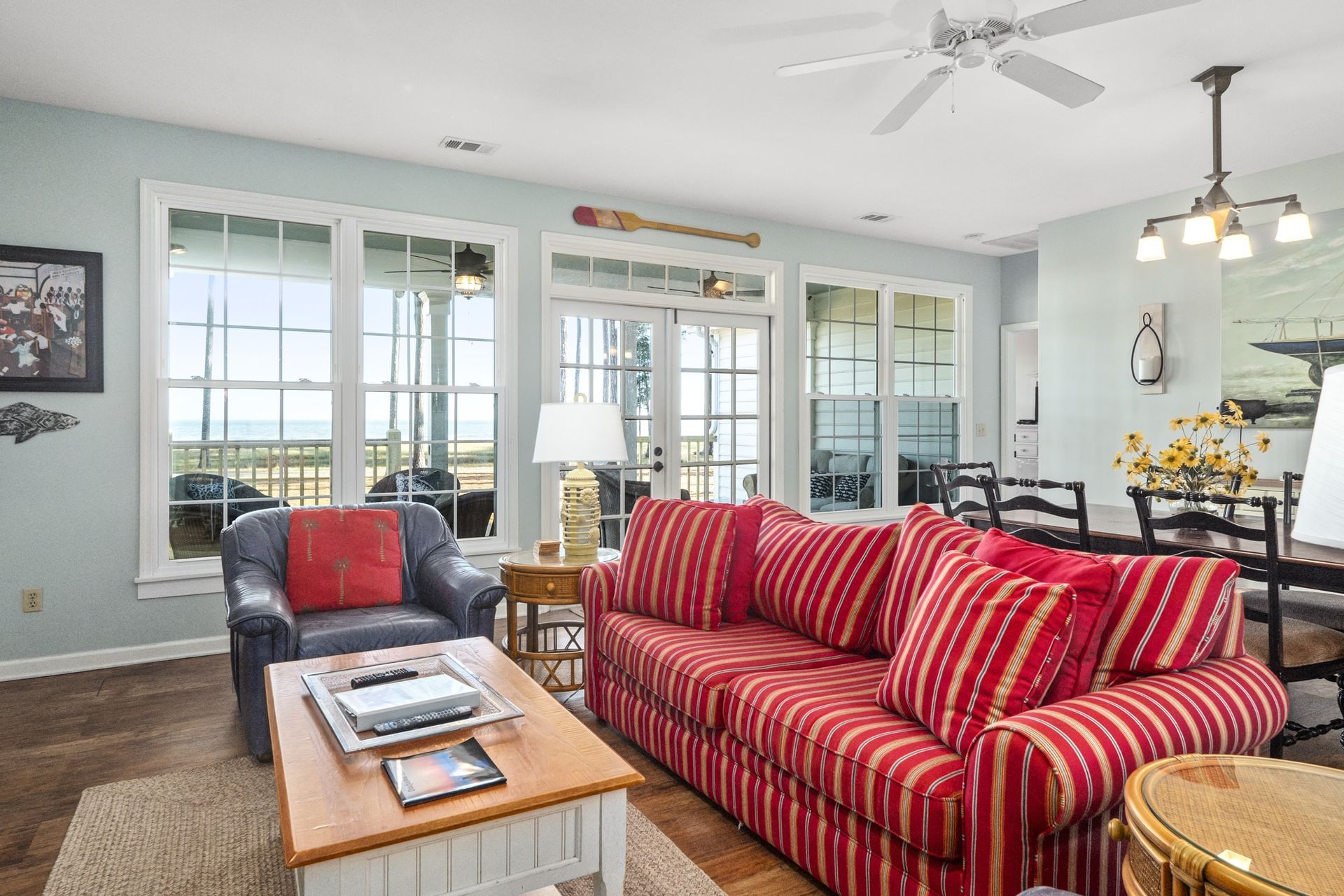 A living room with a red couch , chair , coffee table and ceiling fan.