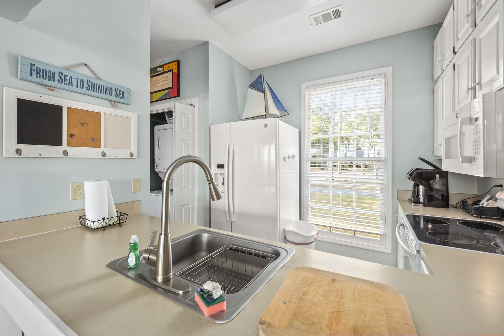 A kitchen with a sink , refrigerator , stove and microwave.