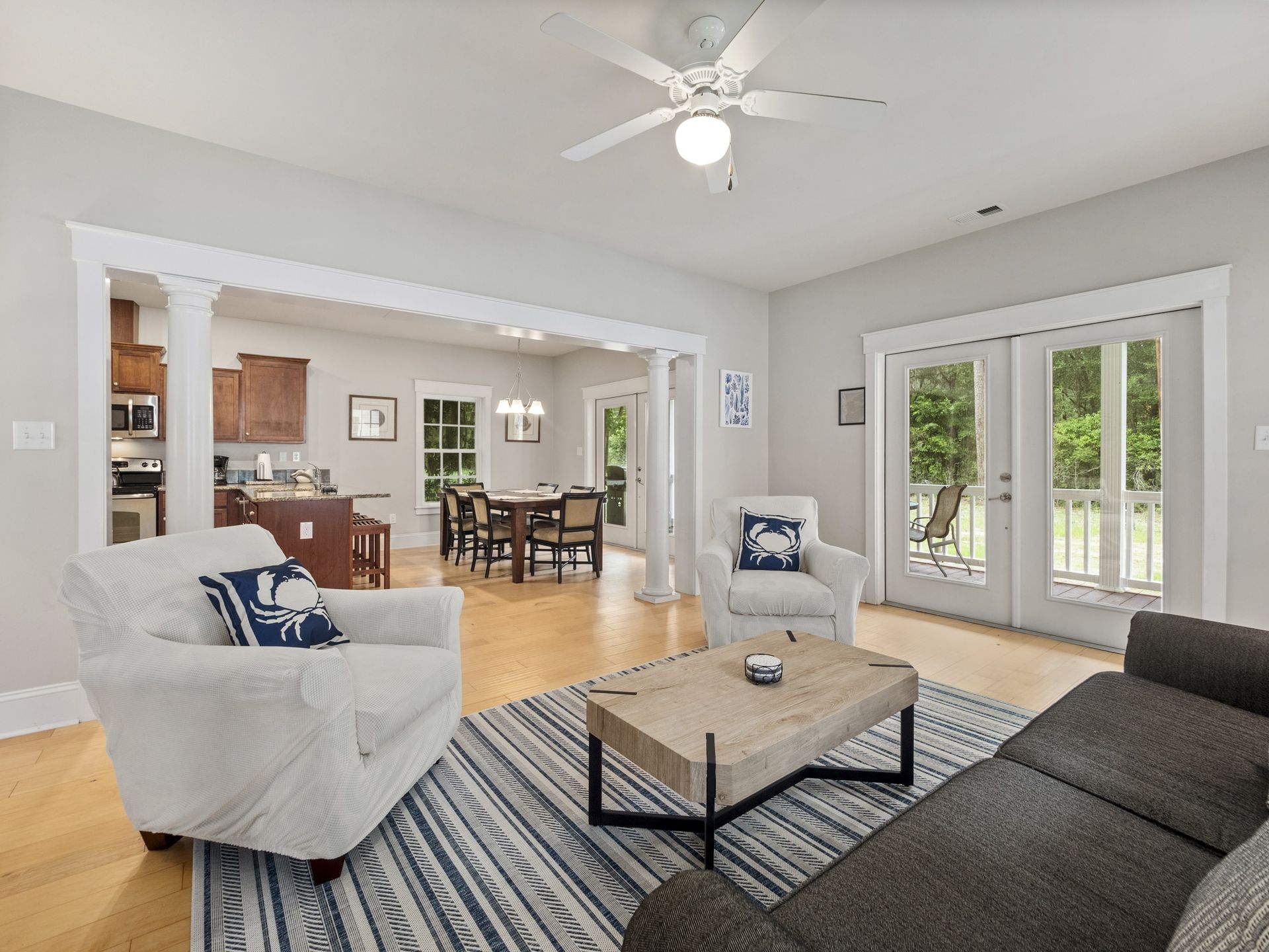 A living room with a couch , chairs , coffee table and ceiling fan.