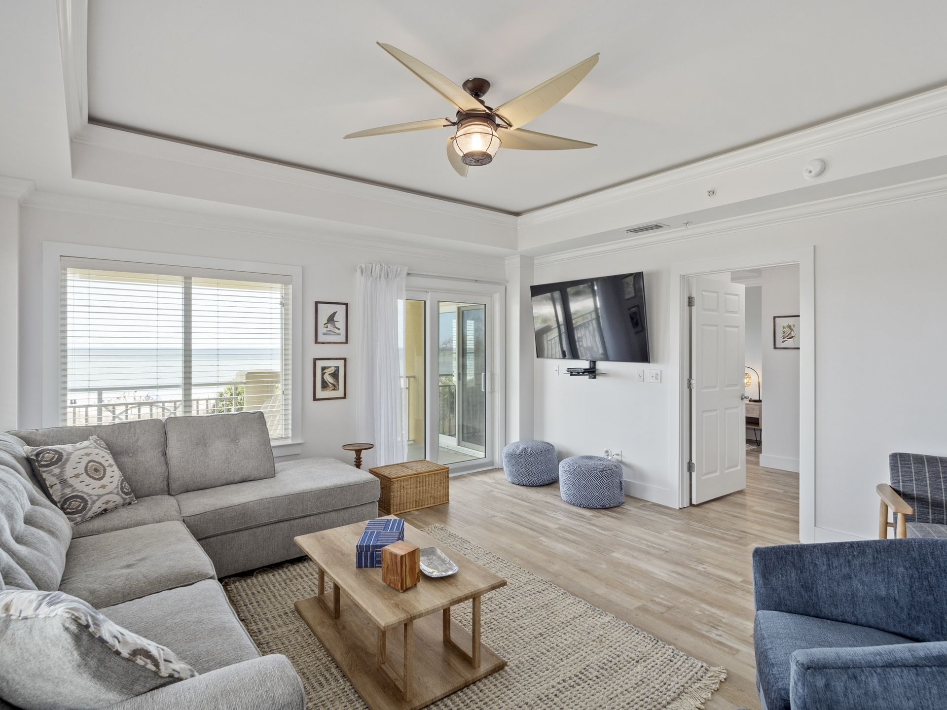 A living room with a couch , chair , coffee table , television and ceiling fan.