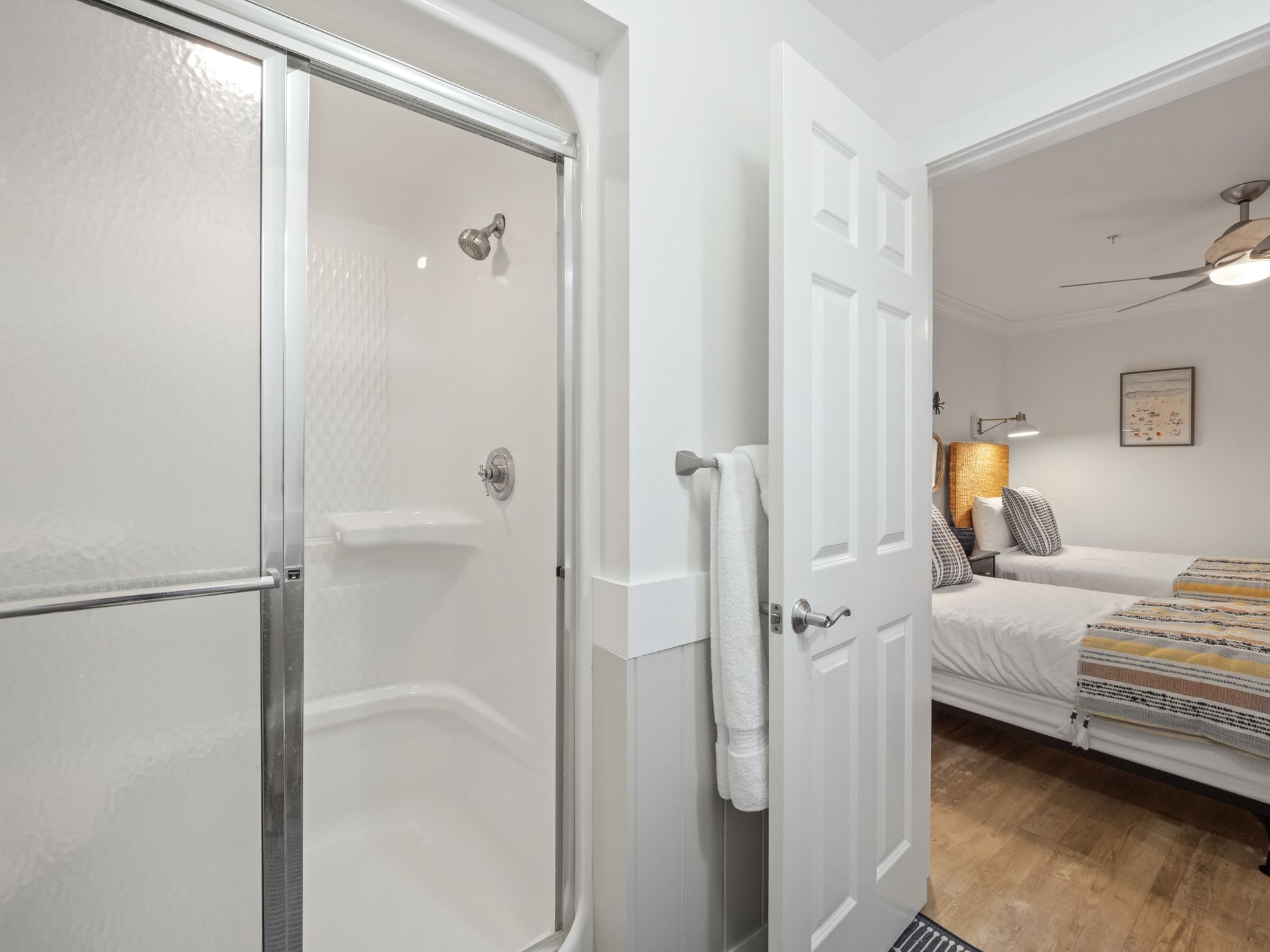 A bathroom with a walk in shower and two beds.