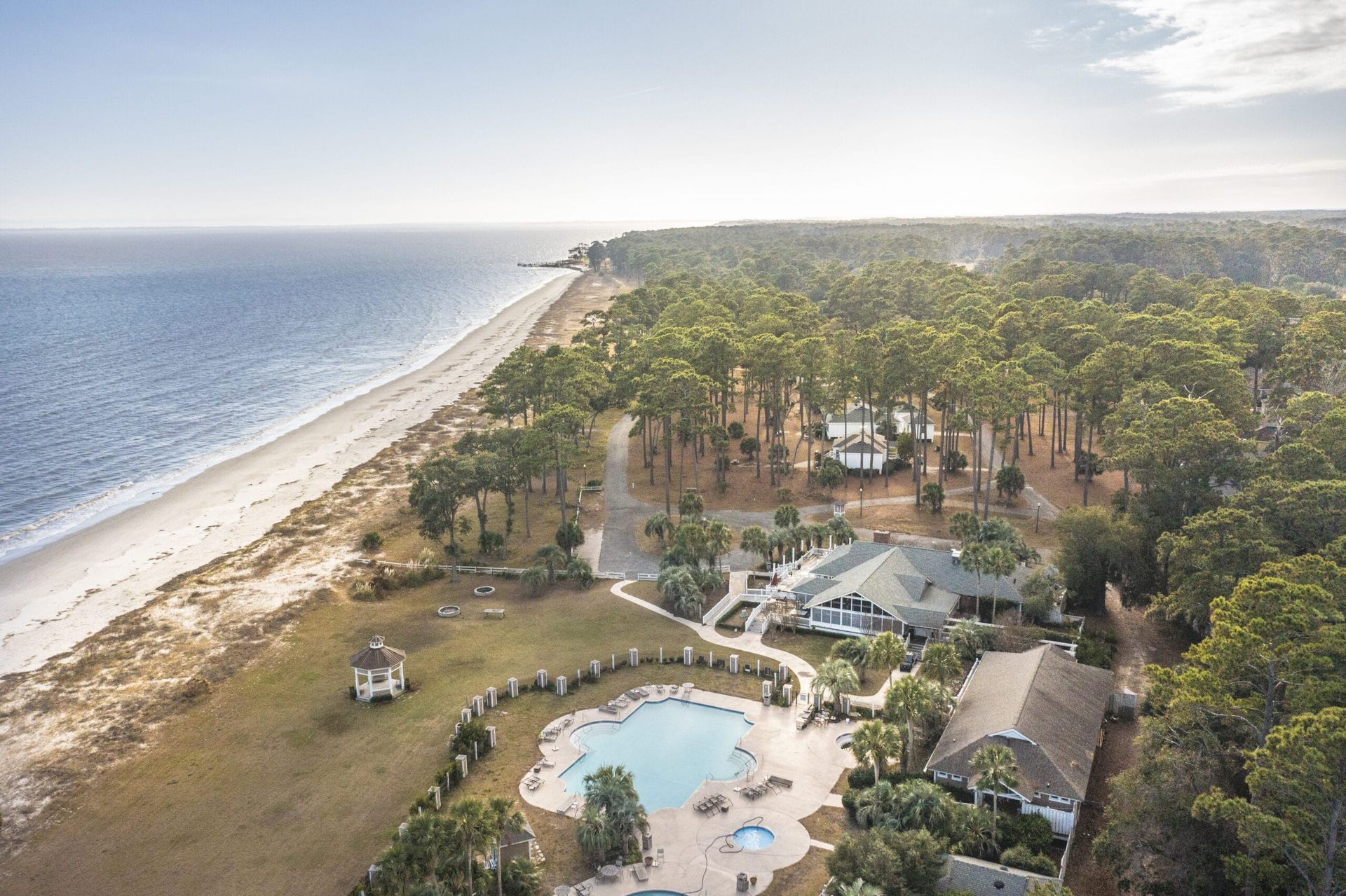 An aerial view of a beach with a house and a pool