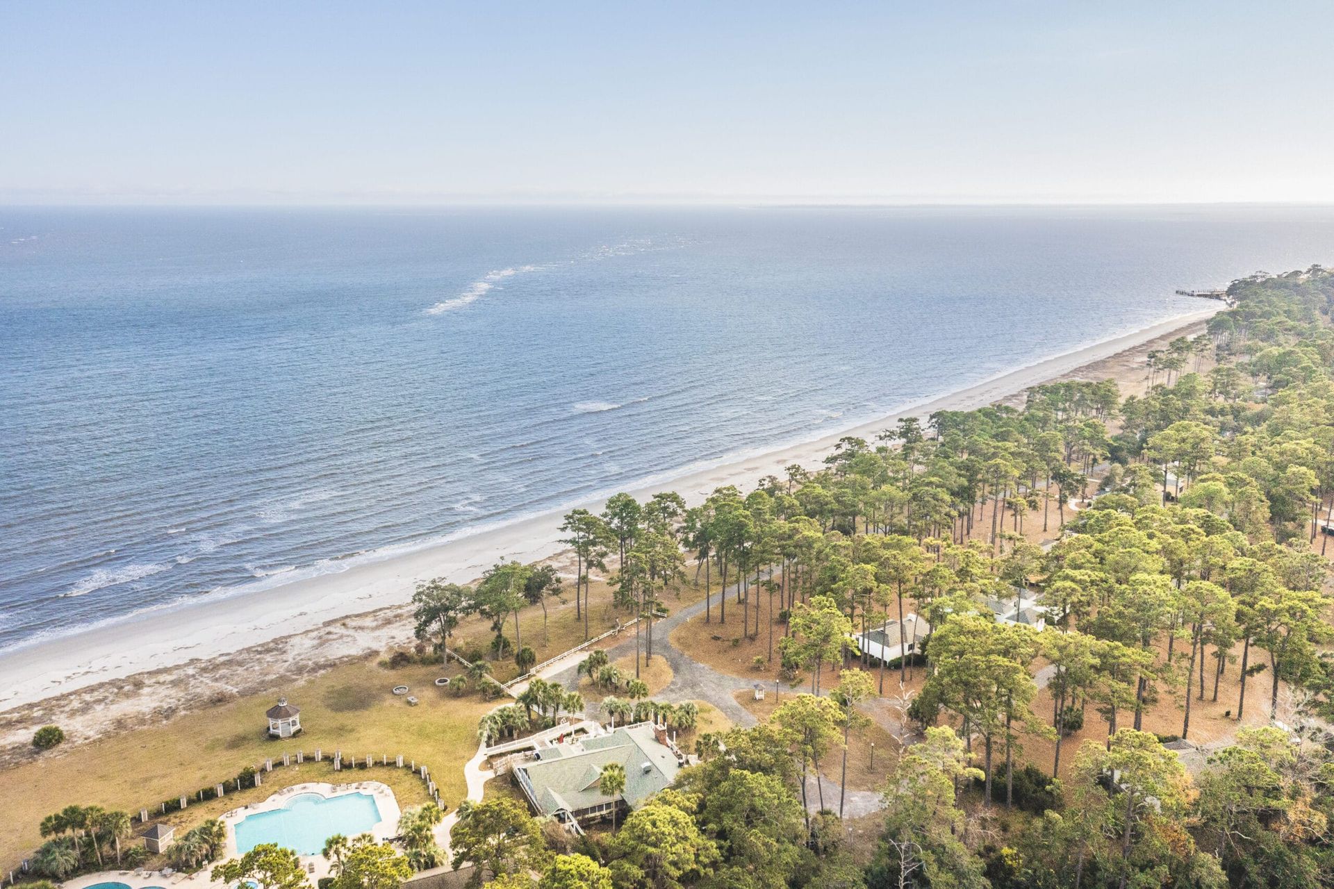 An aerial view of a beach with trees and a pool.