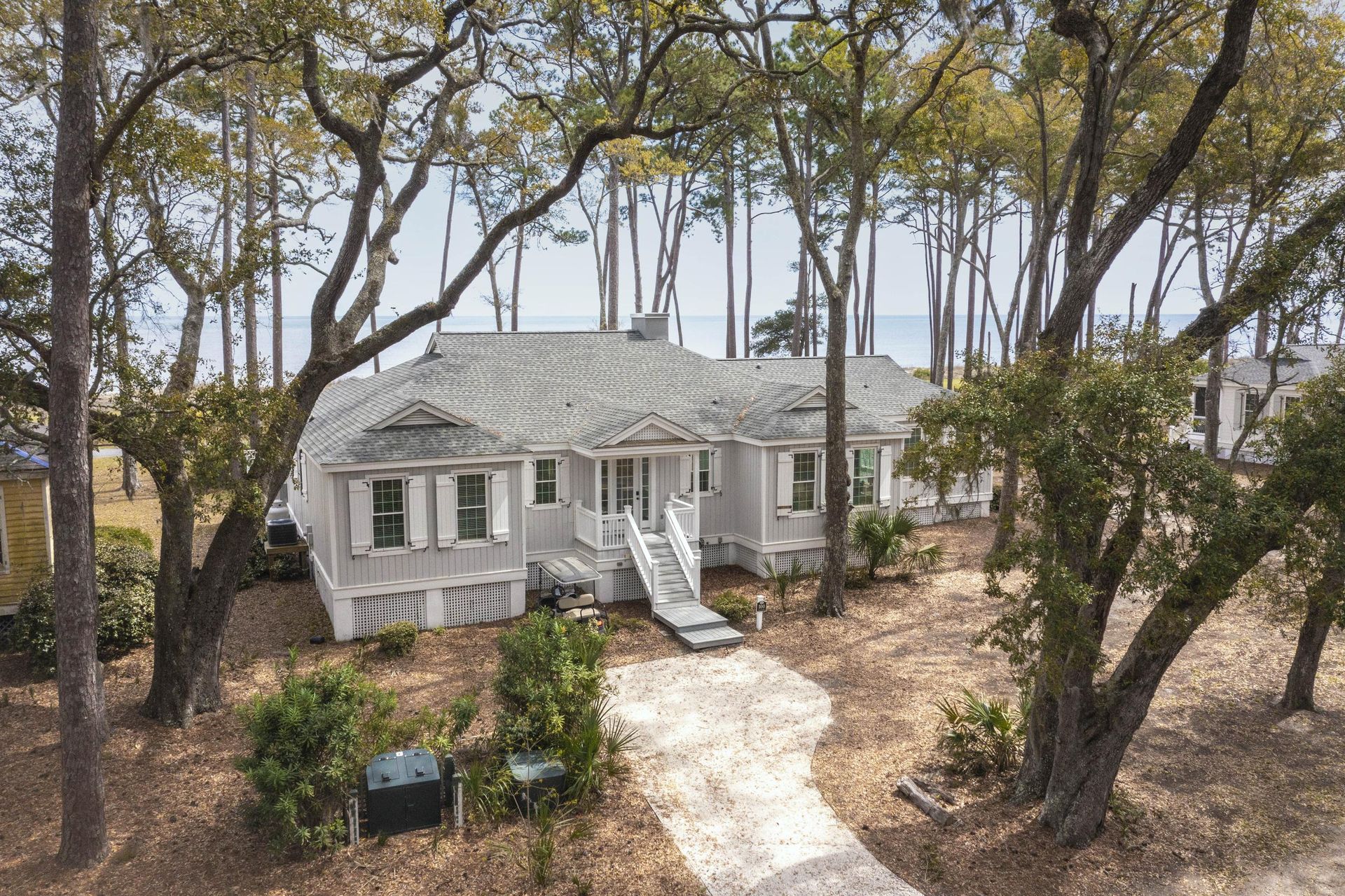 An aerial view of a white house surrounded by trees.