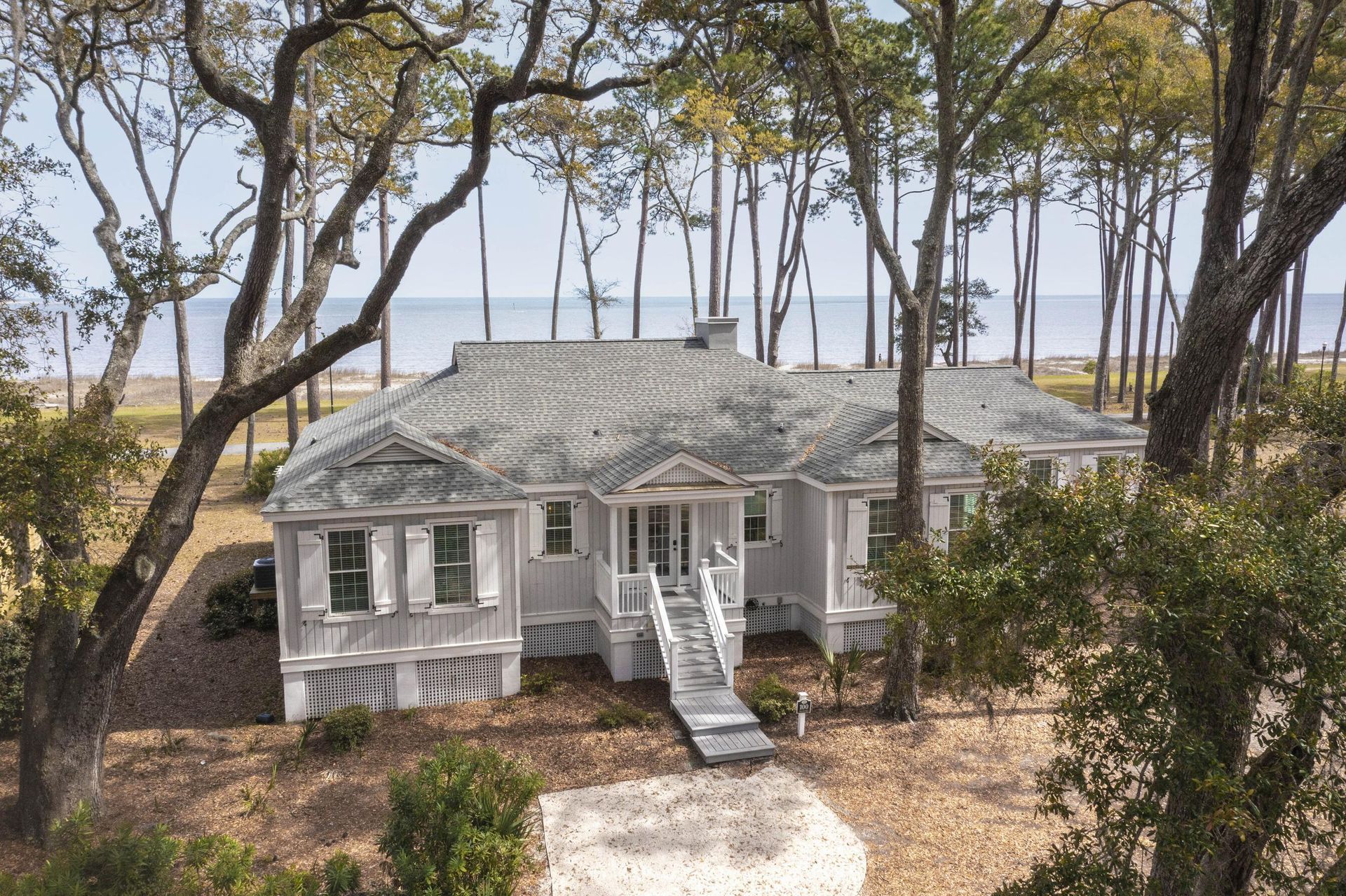 An aerial view of a white house surrounded by trees.